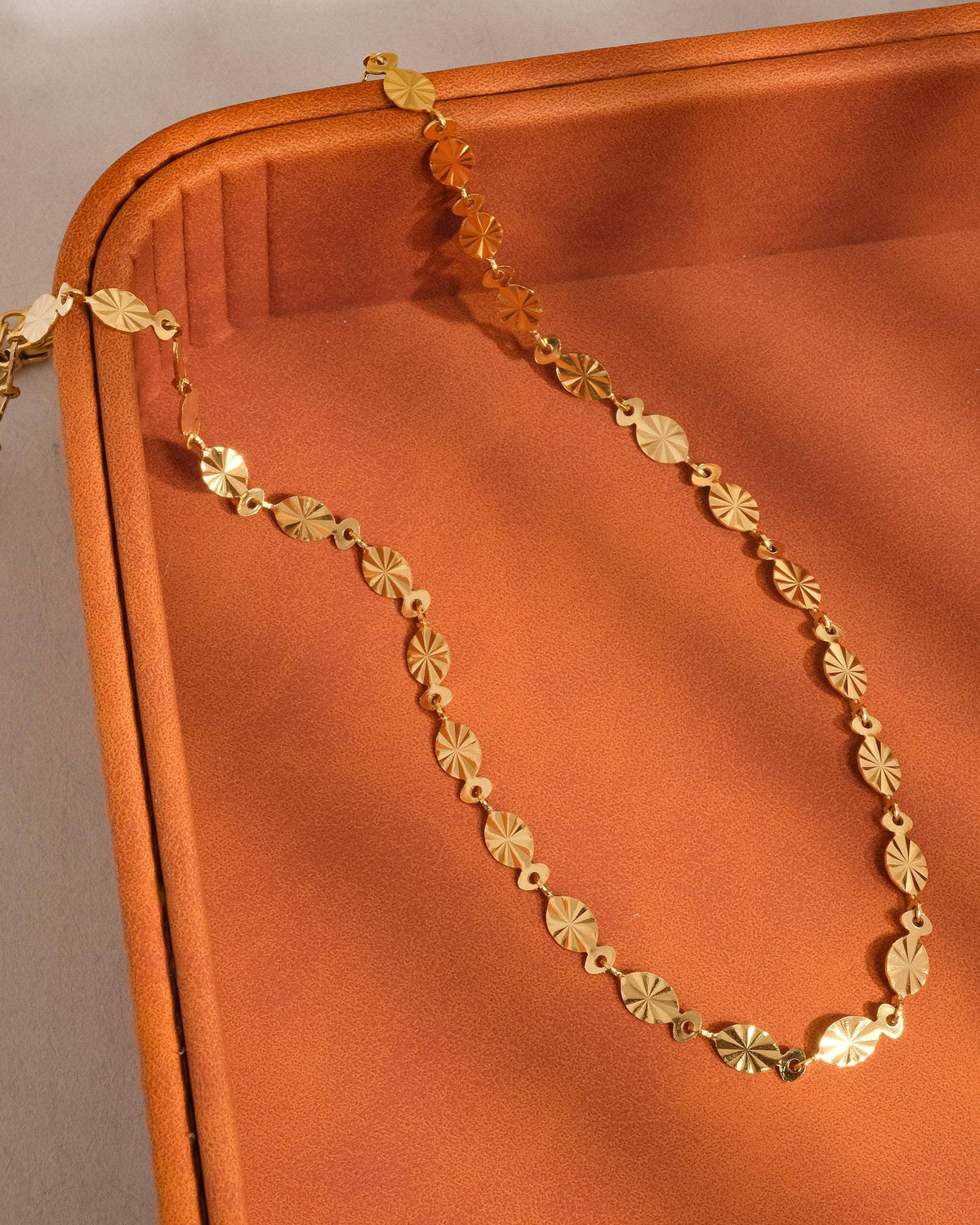 Gold chain on a textured orange surface