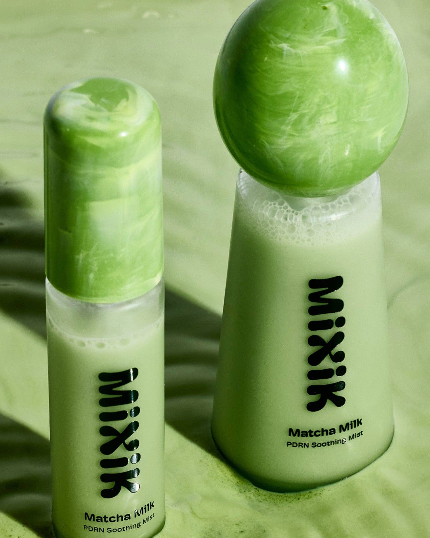 Two bottles of MIXIK Matcha Milk on a green surface with a marble effect.