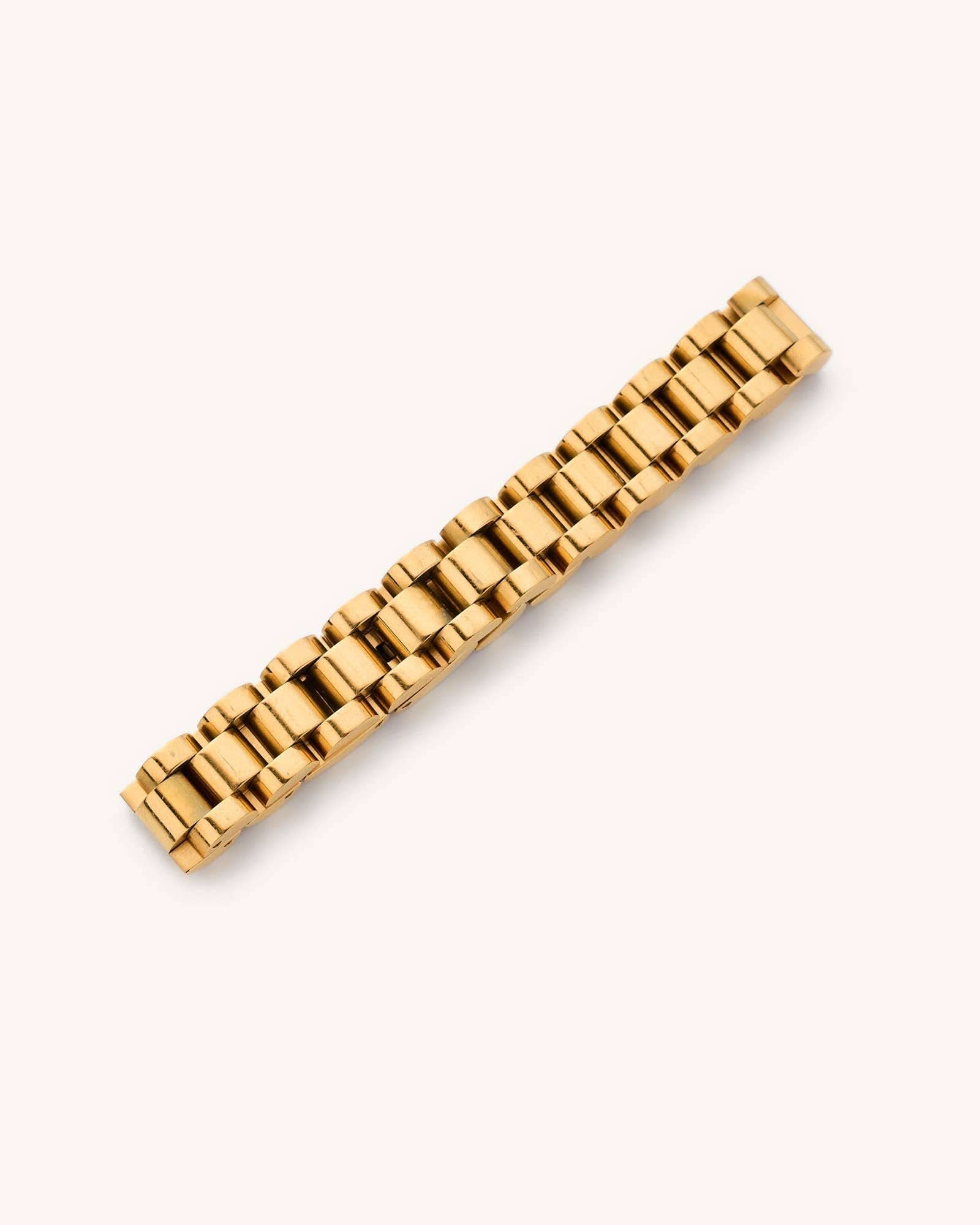 Gold watchband bracelet laying in a white background