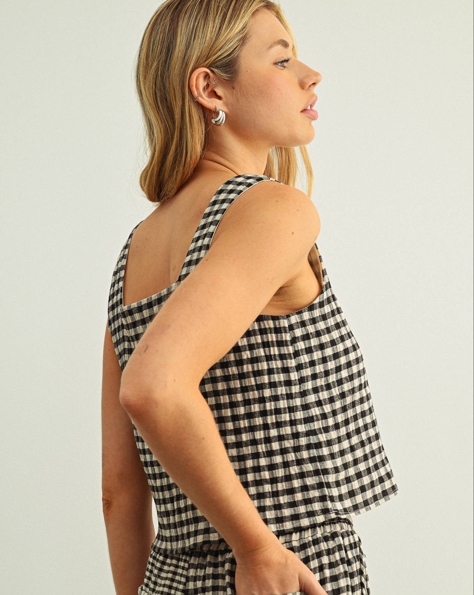Woman wearing a black and white checkered jumpsuit against a plain background