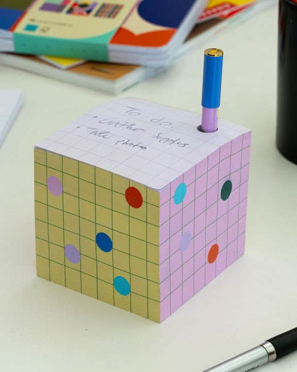 Colorful sticky note block with a hole to contain pen sitting on a desk