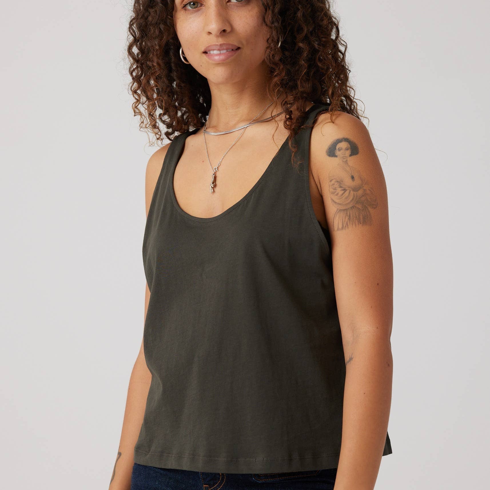 Woman wearing a dark green tank top against a plain background