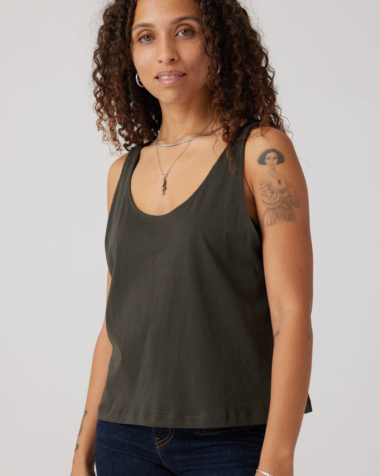Woman wearing a dark green tank top against a plain background