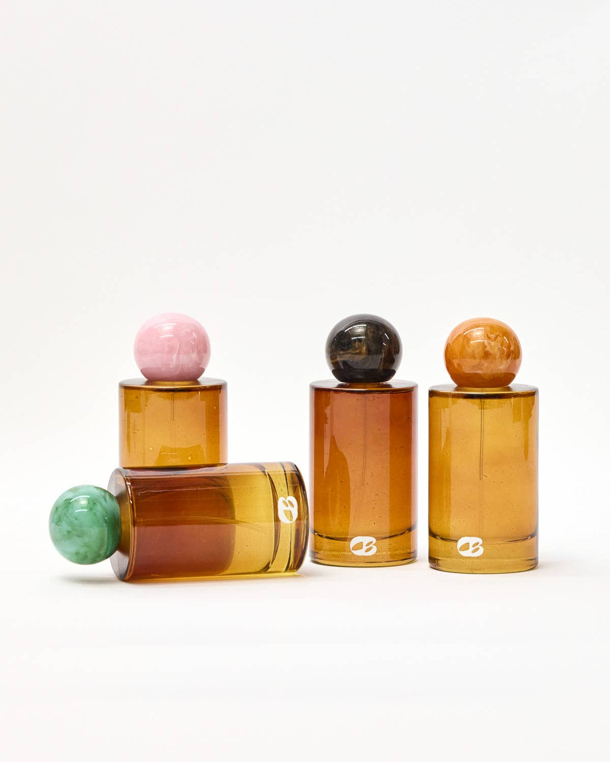 Set of amber glass bottles with colorful spherical tops on a white background