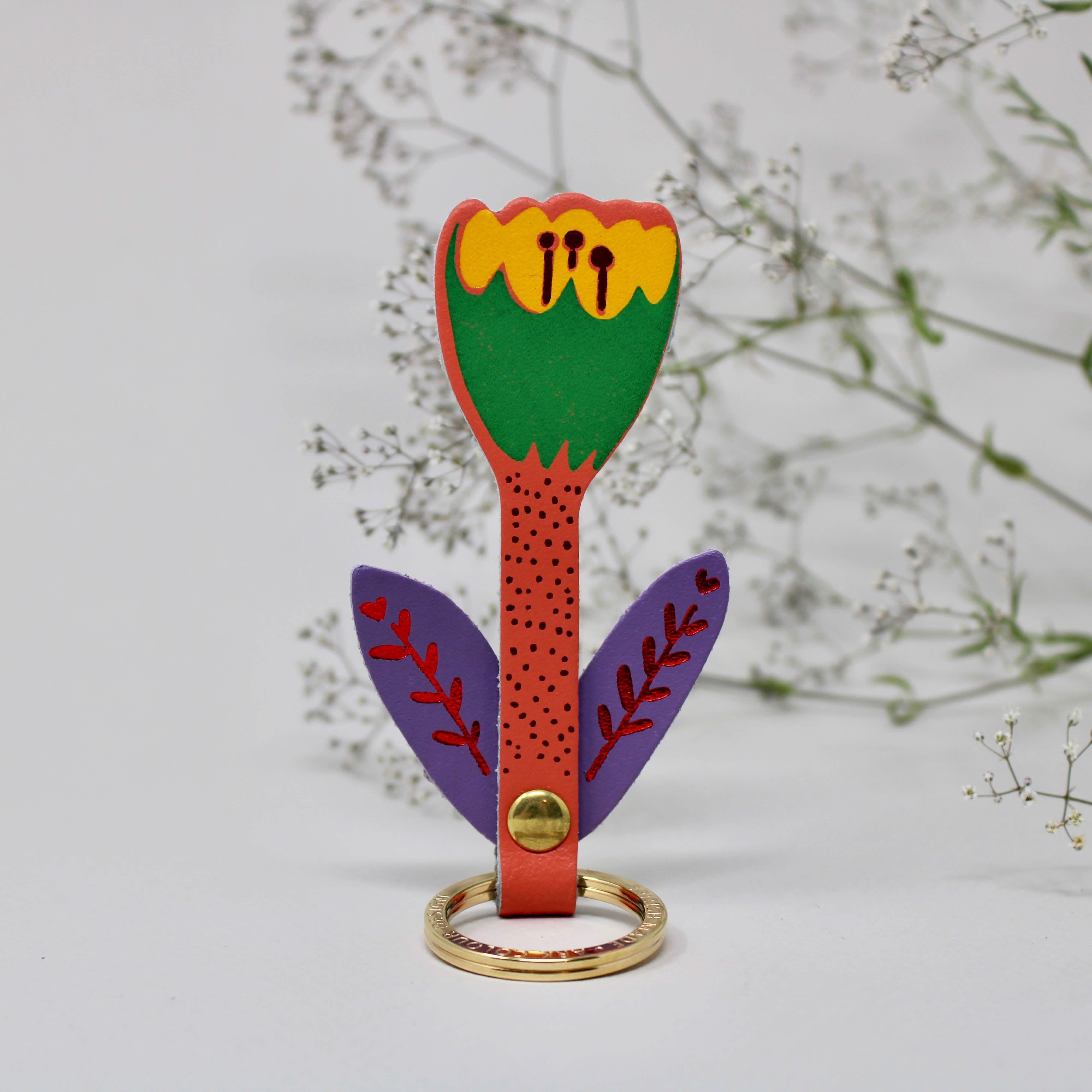 Colorful tulip keychain behind foliage background.