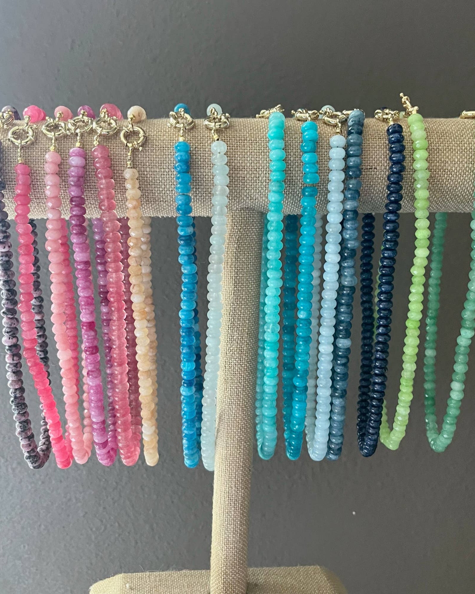 Set of colorful beaded necklaces on a display stand against a gray background