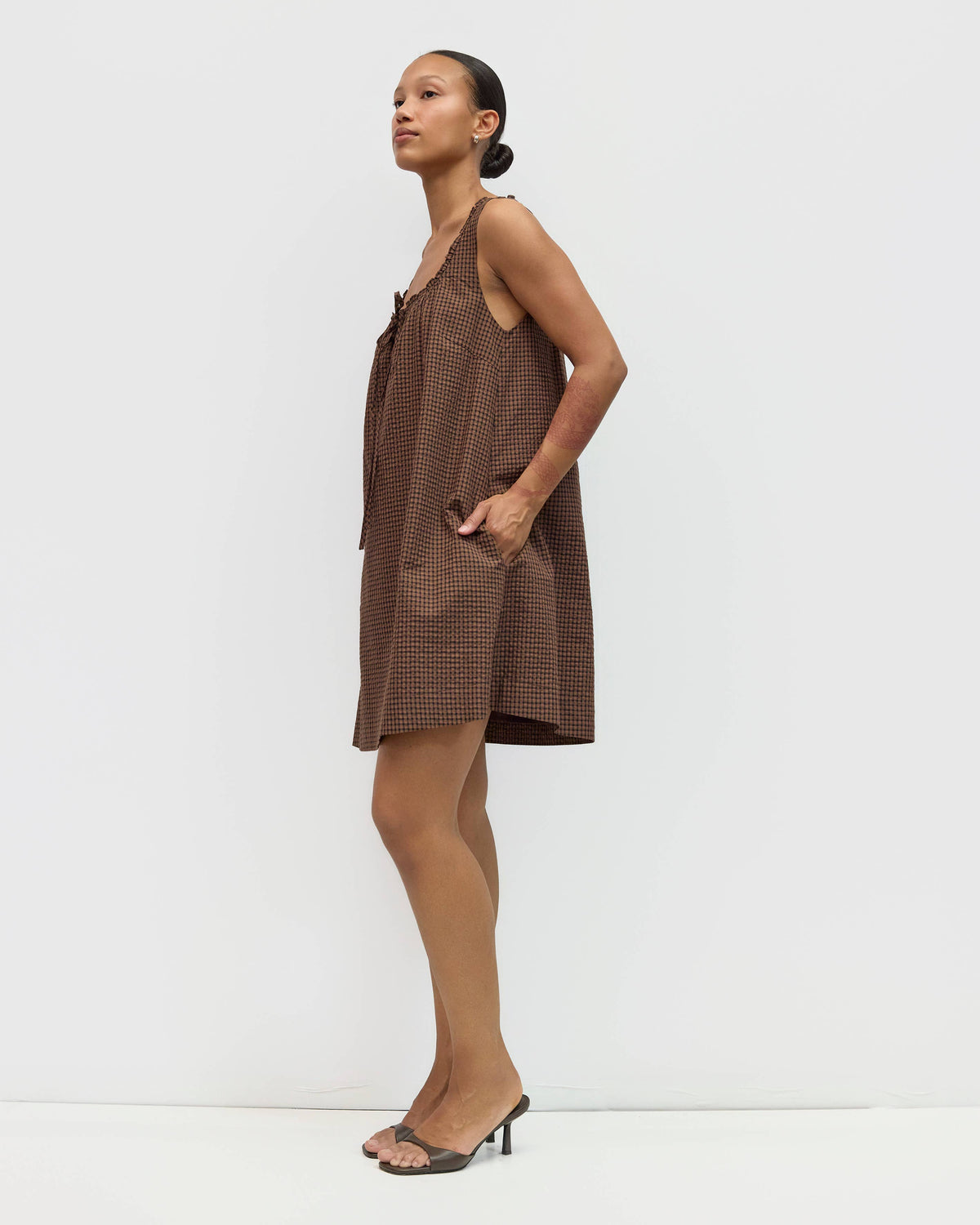 Woman wearing a brown checkered dress against a white background