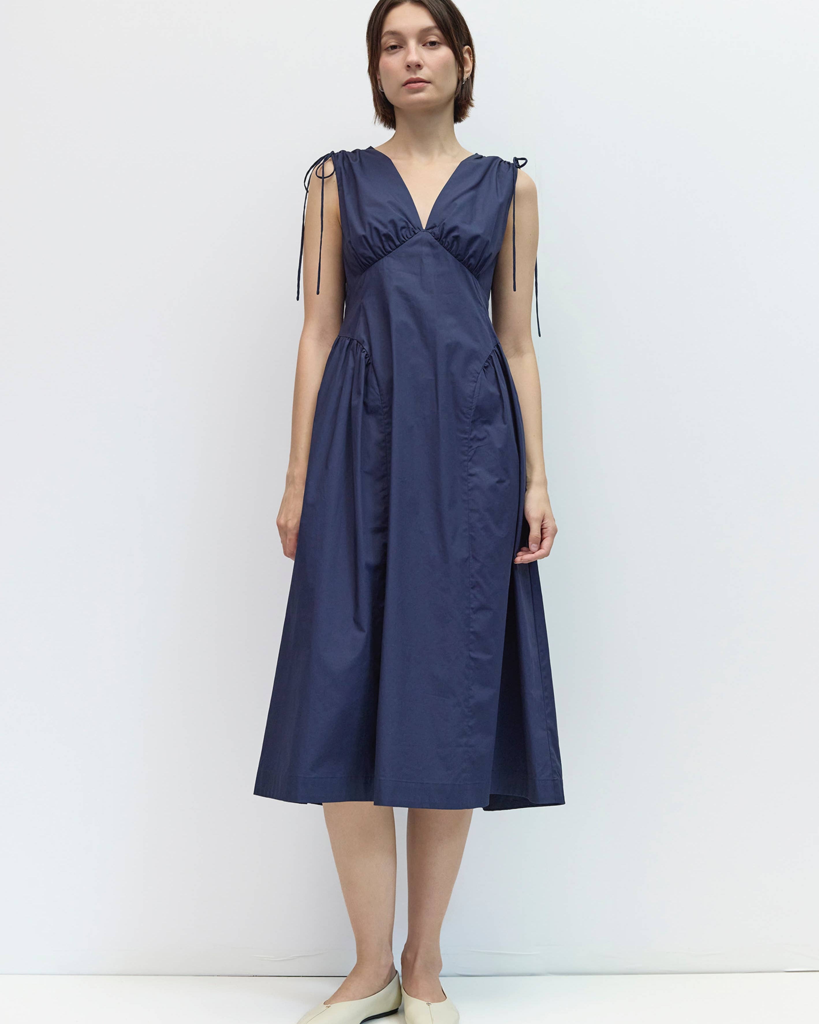 Woman wearing a navy blue dress against a white background