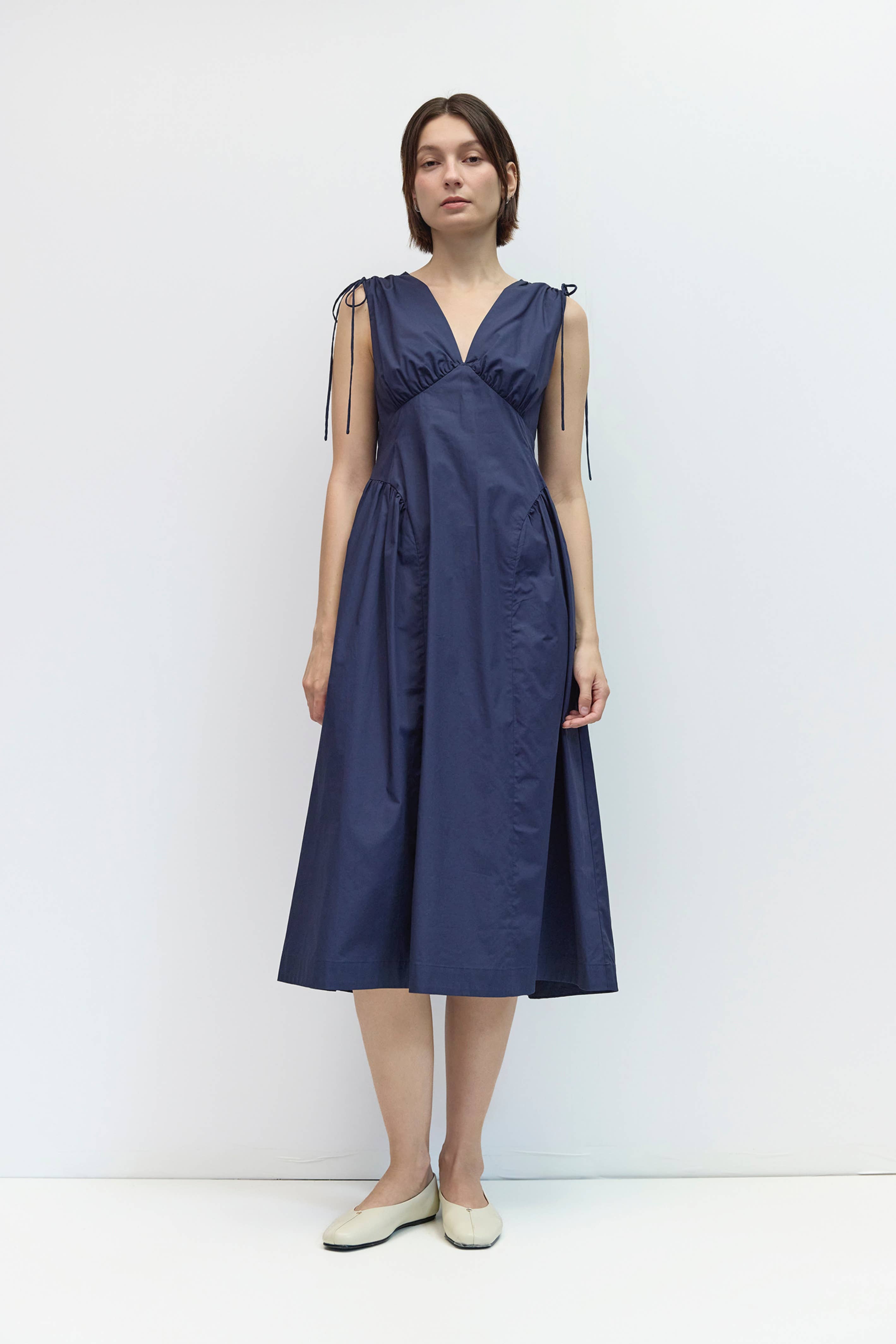 Woman wearing a navy blue dress against a white background