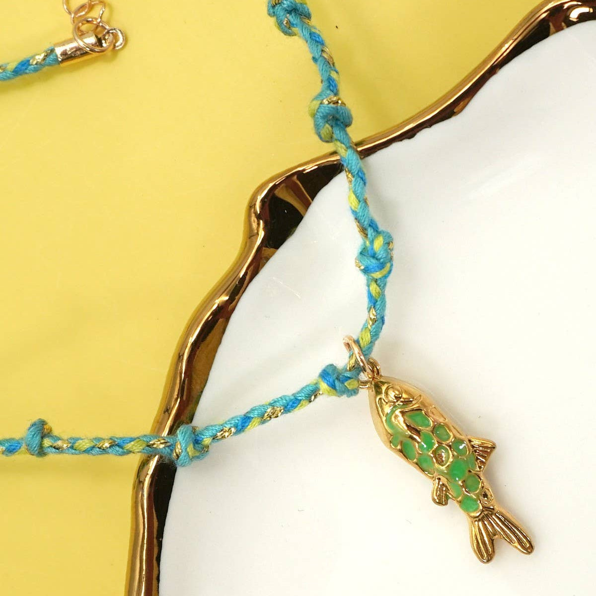 Necklace with a fish charm on a yellow and white background