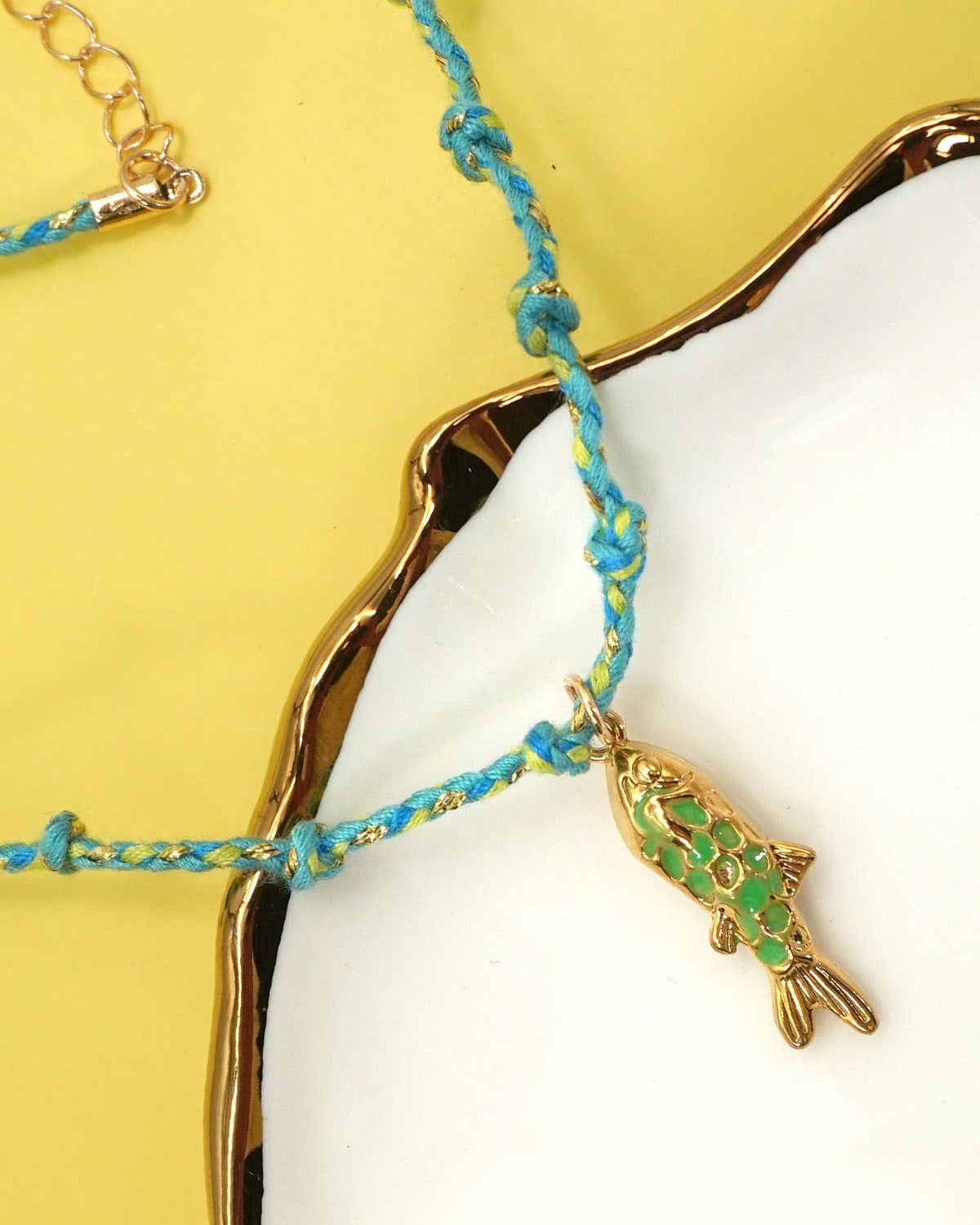 Necklace with a fish charm on a yellow and white background