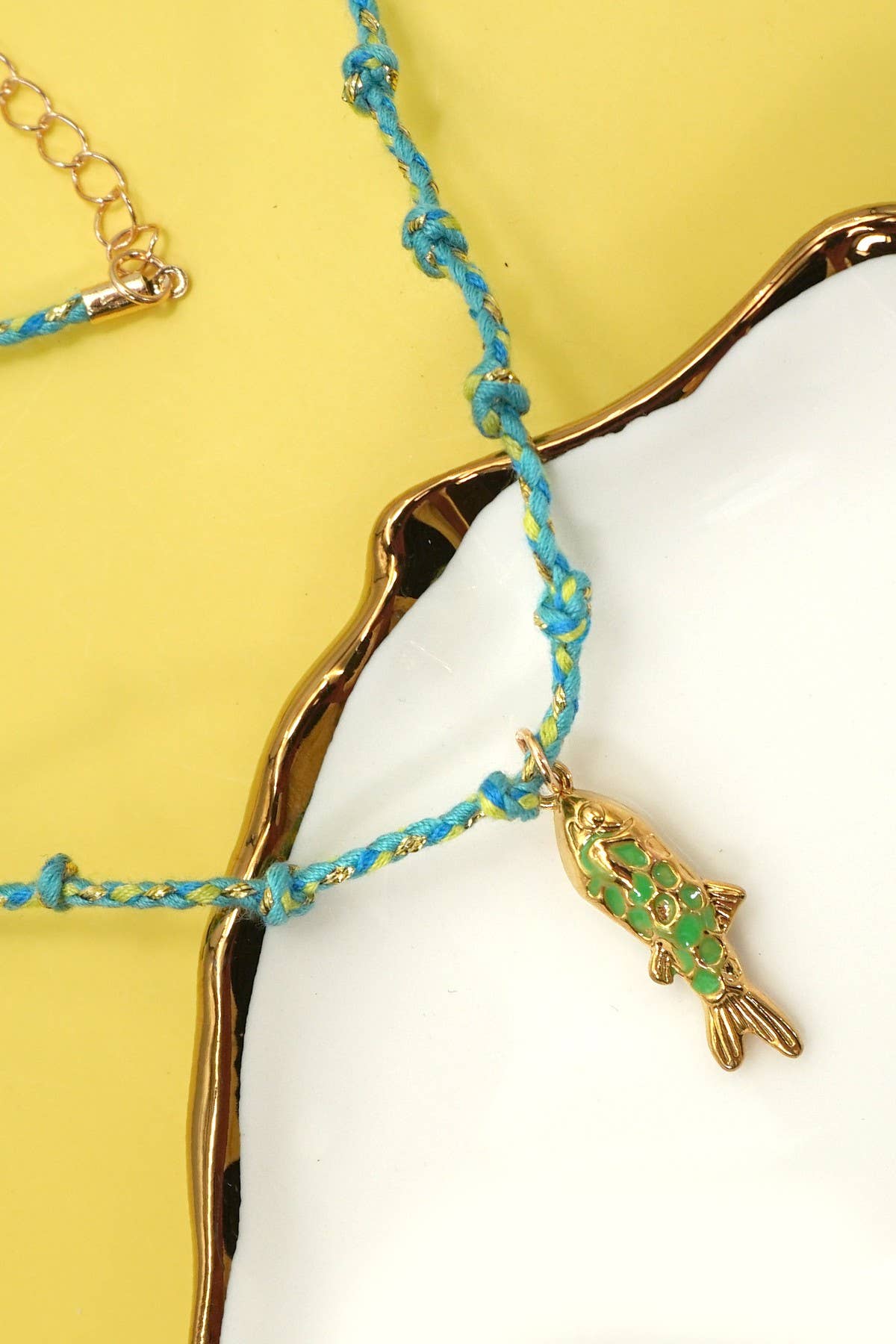 Necklace with a fish charm on a yellow and white background