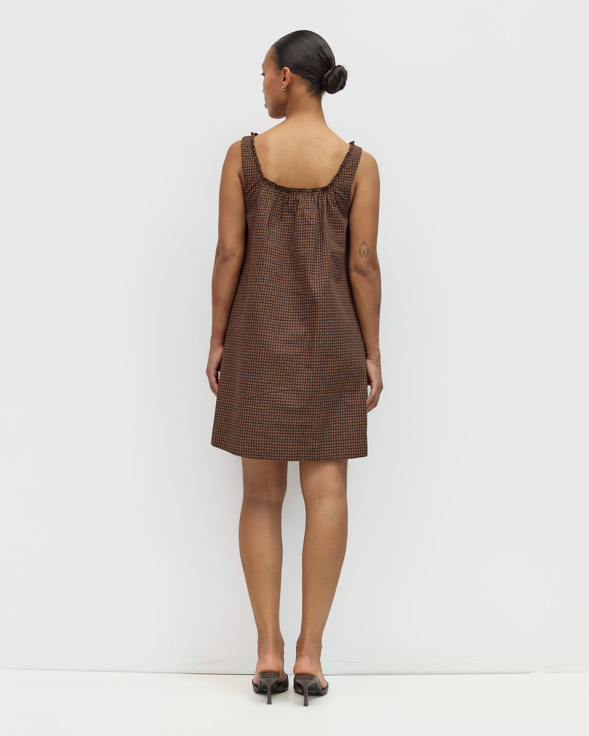Woman wearing a brown checkered dress against a white background