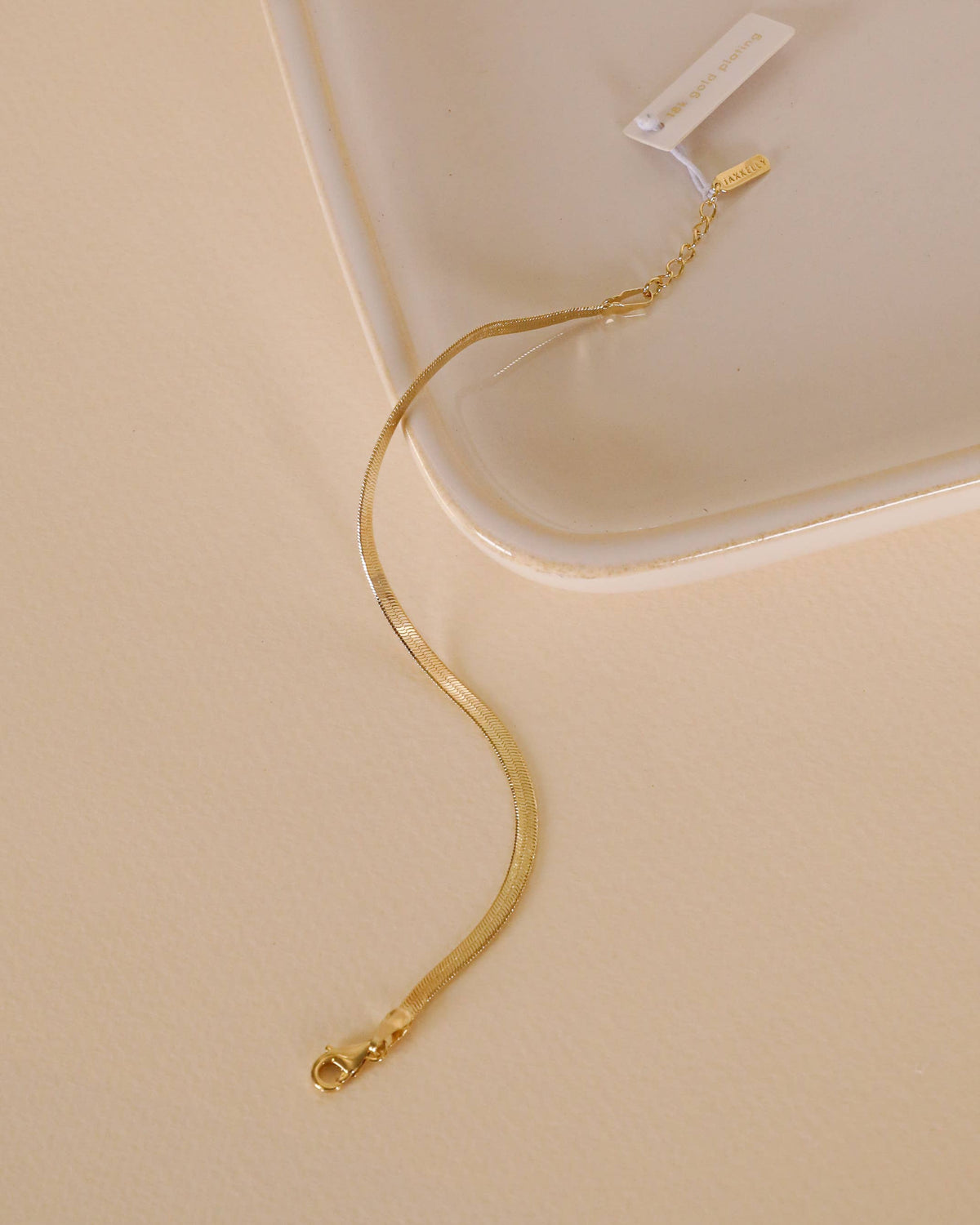 Gold bracelet on a beige surface with a white background