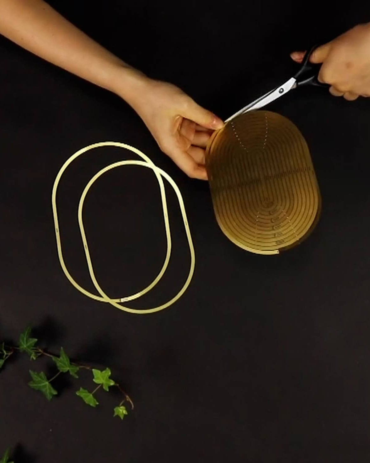 Person cutting a woven basket with scissors on a dark surface