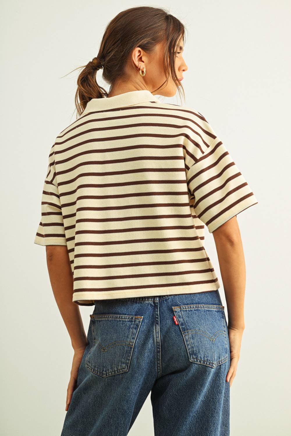 Person wearing a striped shirt and jeans against a plain background