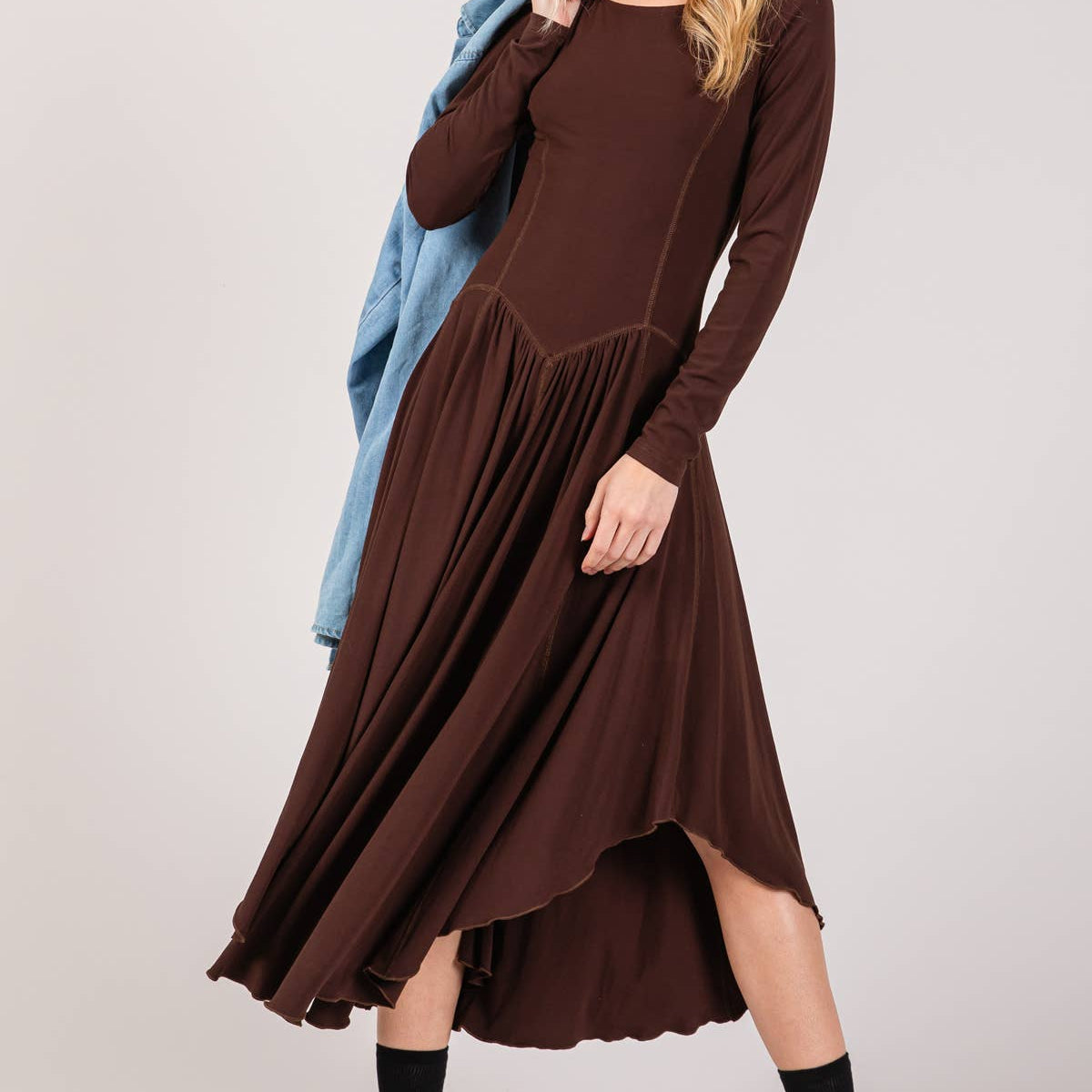 Woman wearing a brown dress with a blue shawl over her shoulder on a white background