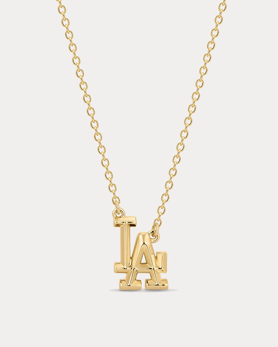 Gold necklace with 'LA' pendant on a light gray background