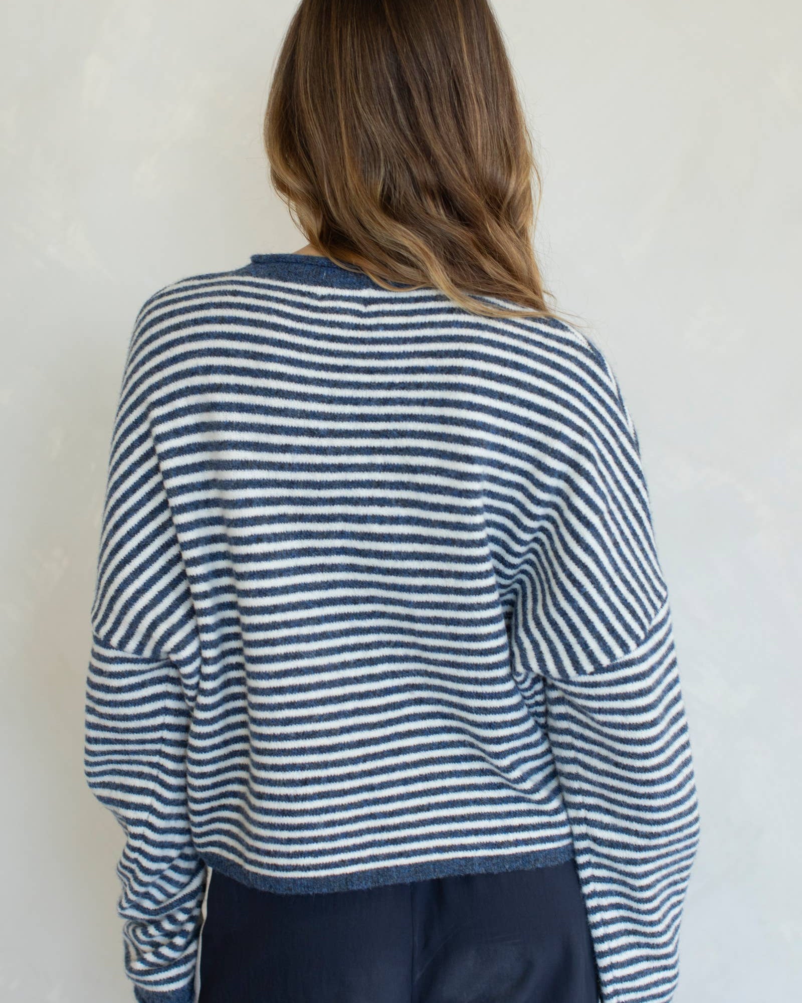 Person wearing a blue and white striped sweater against a plain background