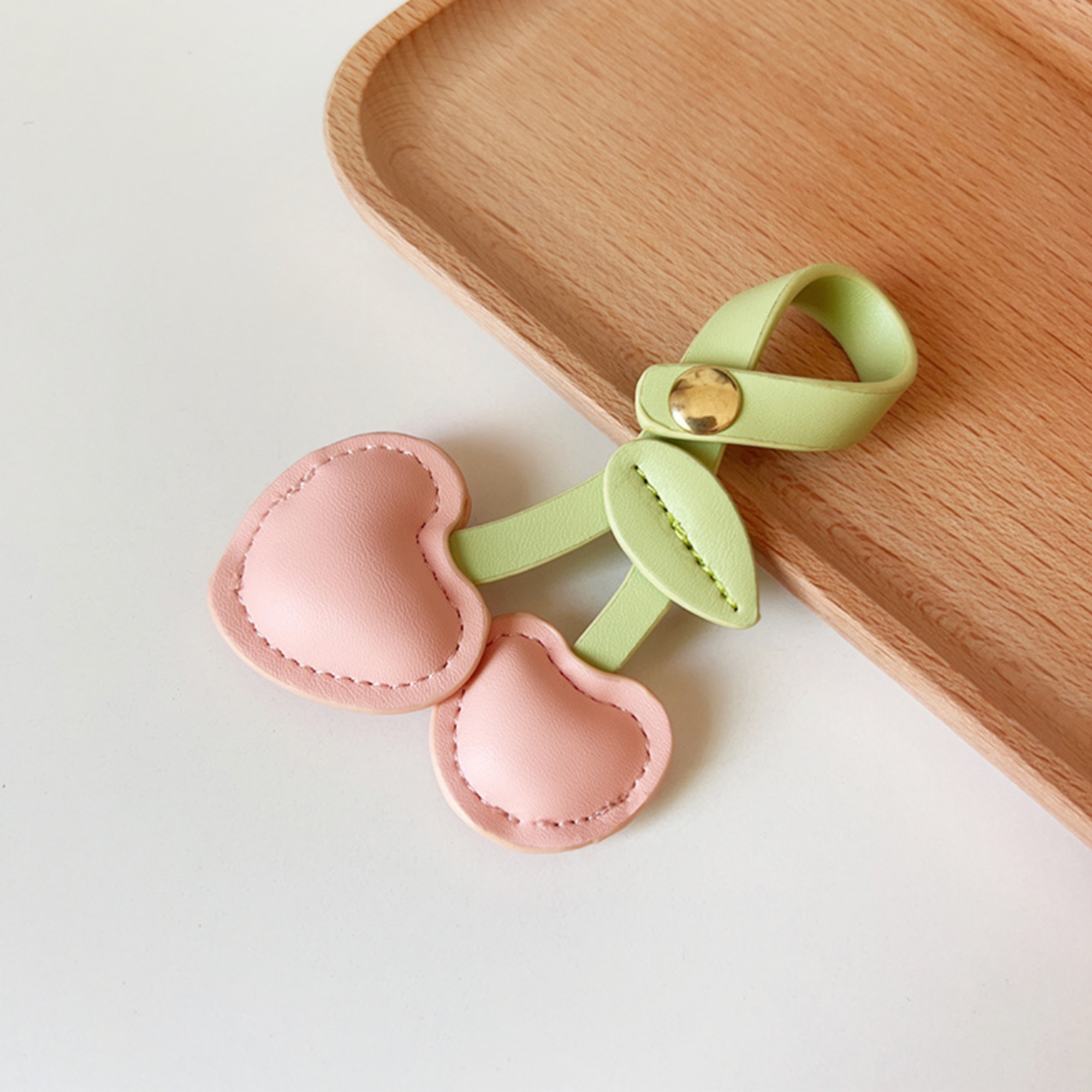 Two Pink leather heart shaped cherries with light green leaf and looped stem and gold button clasp to use as bag charm