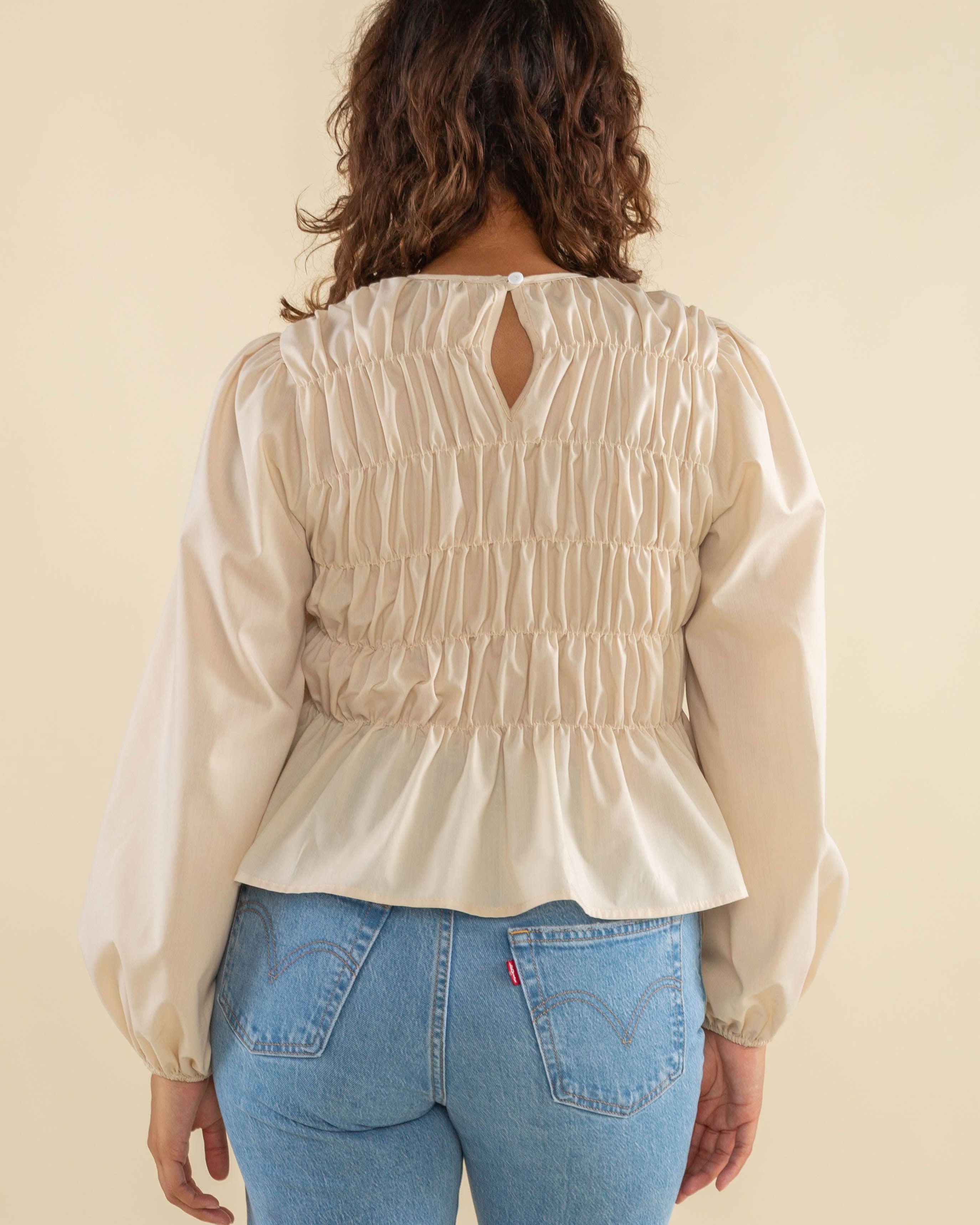 Woman wearing natural cream white color, bubble long sleeve, shirred, peplum style top