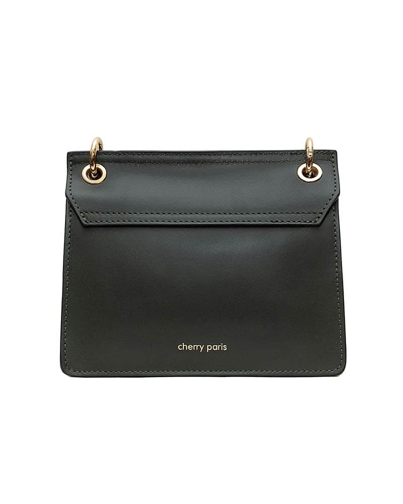 Black leather handbag with gold details and clasp sitting against white background with “cherry Paris” written in gold on the back