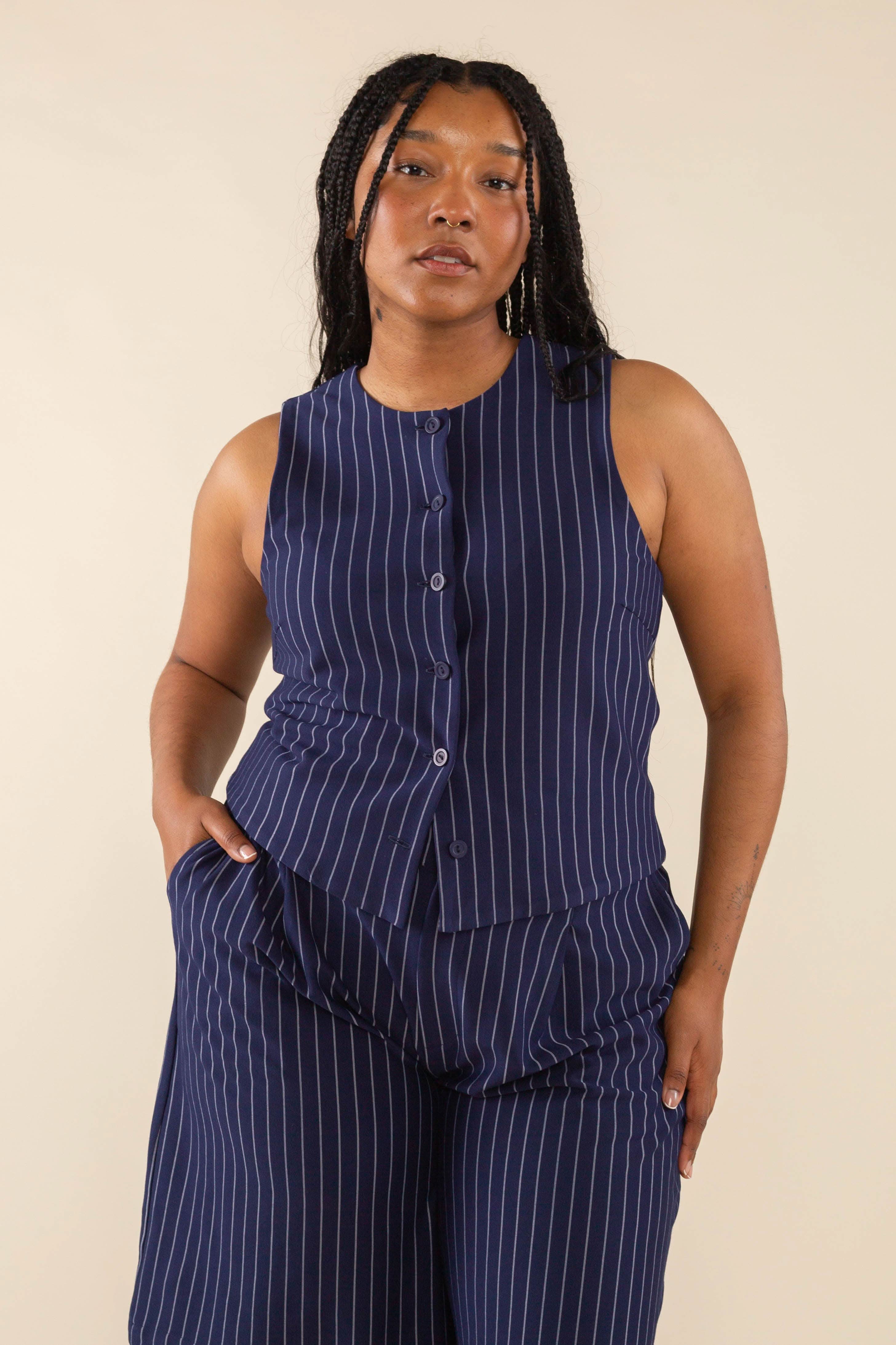 Woman wearing navy blue high neck vest with cream pinstripes. Vest has navy blue buttons all the way down