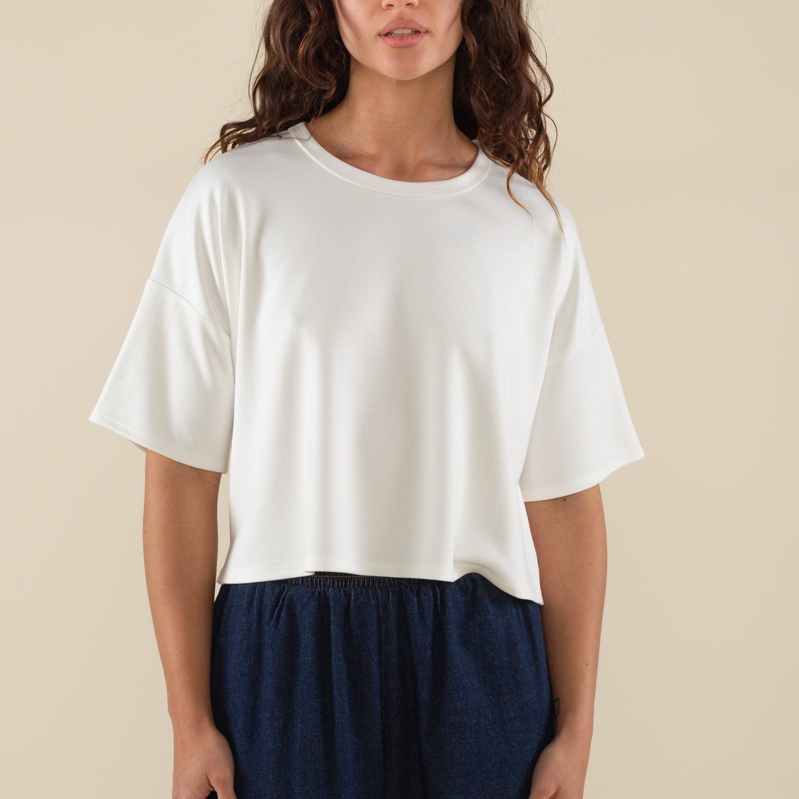Woman wearing white, short sleeve, jersey, cropped t-shirt and blue jeans