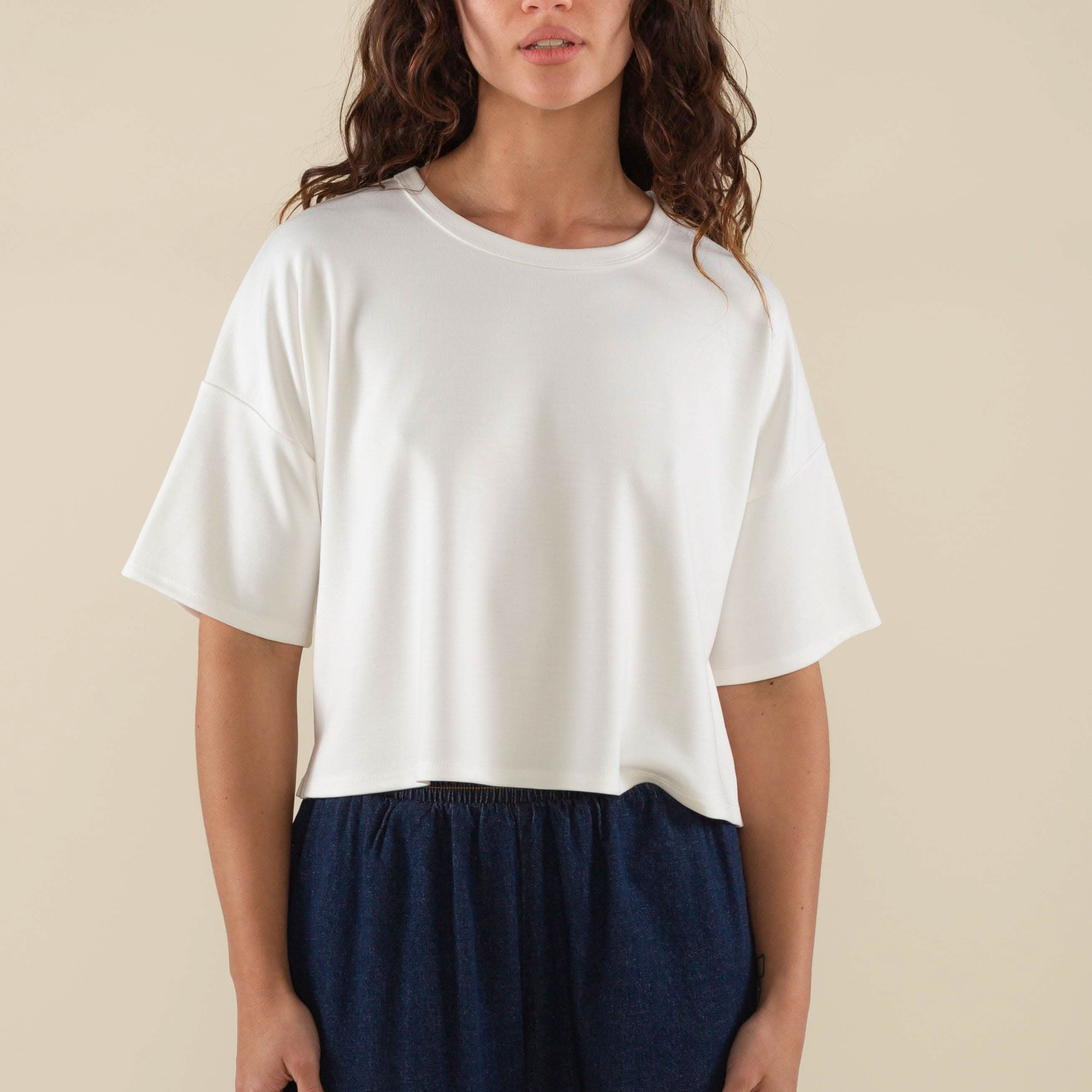 Woman wearing white, short sleeve, jersey, cropped t-shirt and blue jeans