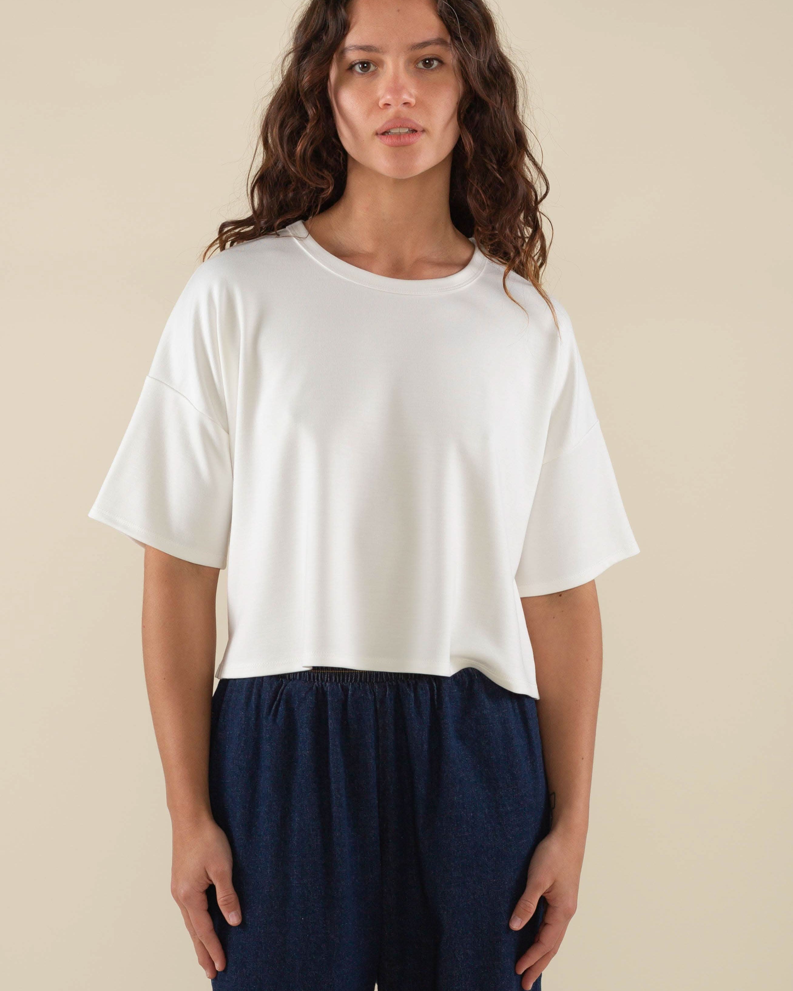 Woman wearing white, short sleeve, jersey, cropped t-shirt and blue jeans