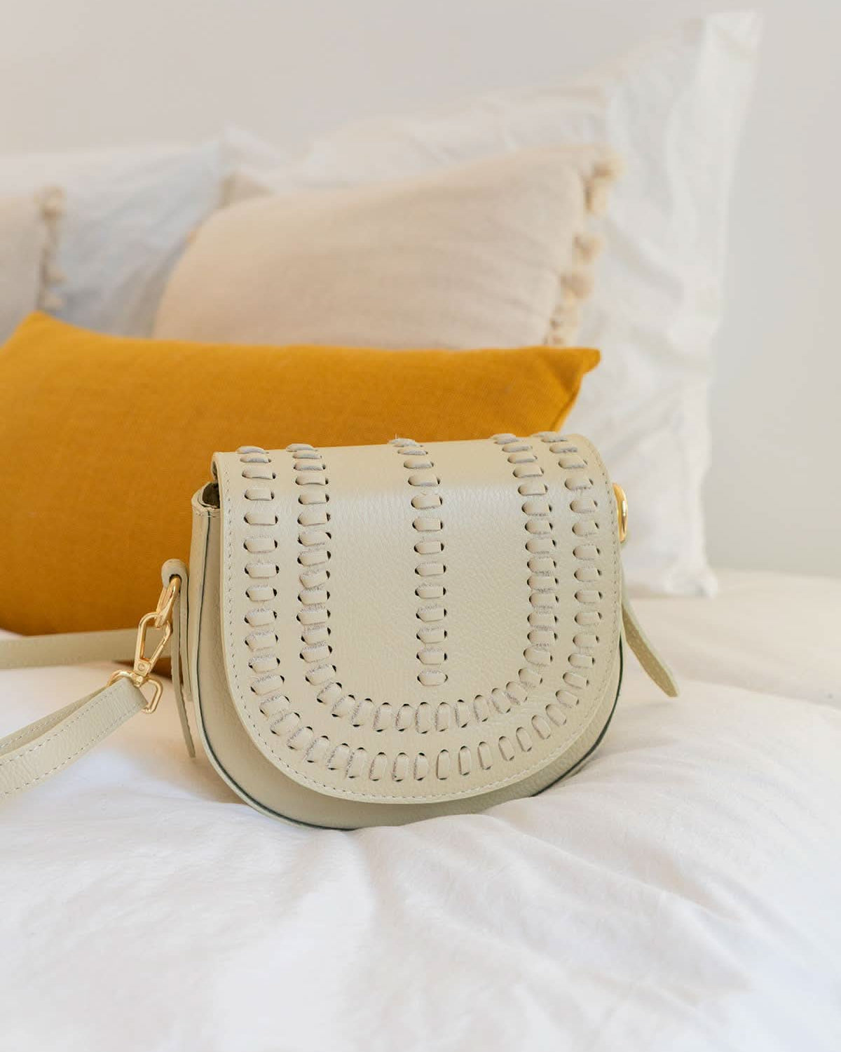 Cream colored leather crossbody bag with magnetic front clap and leather woven geometric details