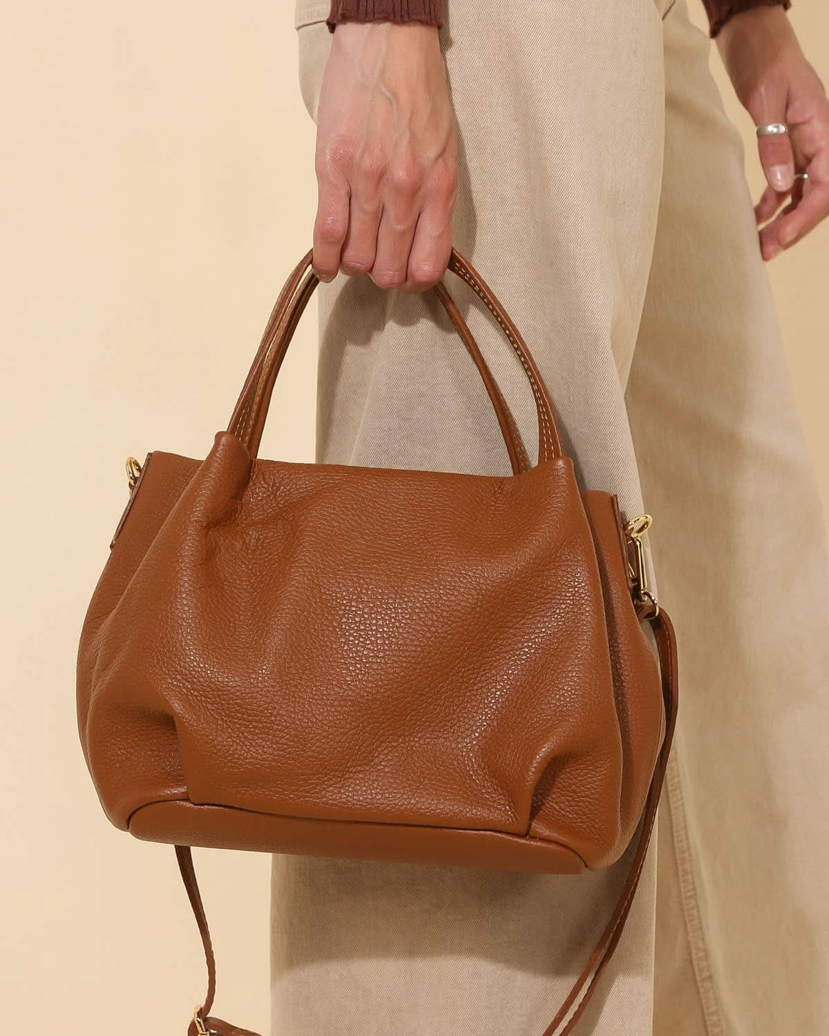 Model holding Big chestnut brown leather handbag purse with handles, strap, and gold details