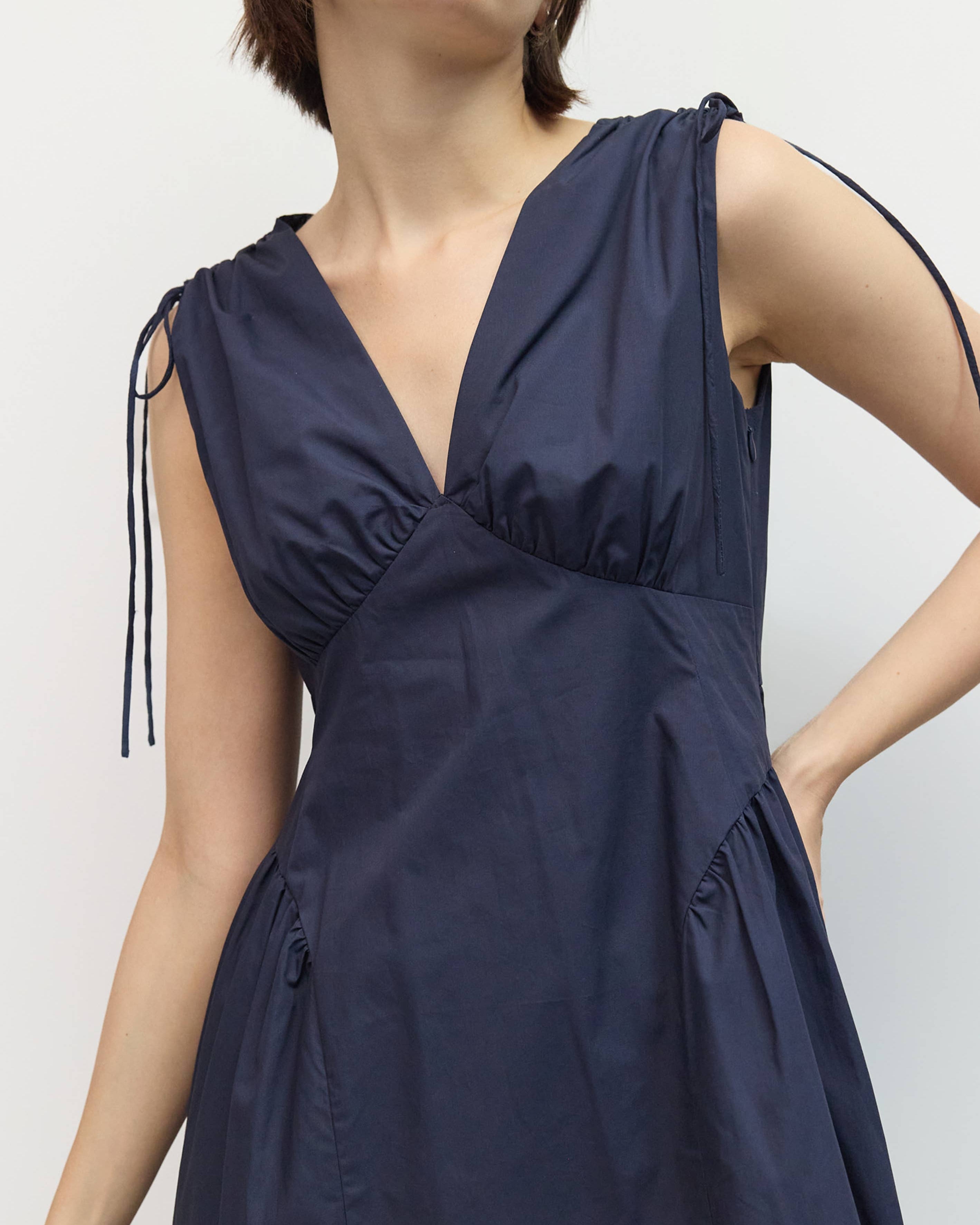 Navy blue dress with shoulder straps on a plain background