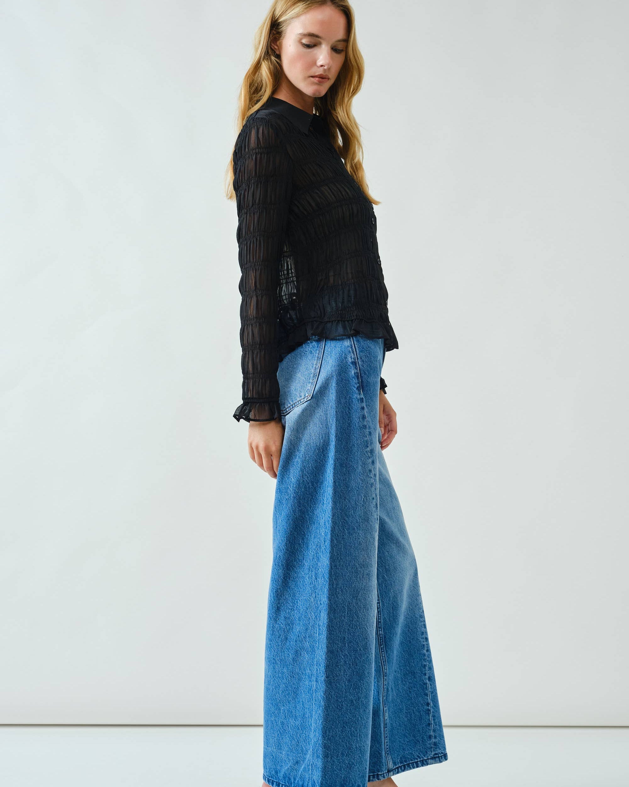 Woman wearing a black top and blue jeans on a white background