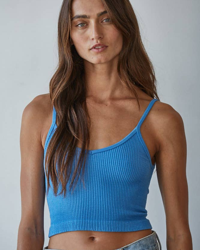 Woman wearing a blue ribbed tank top against a plain background