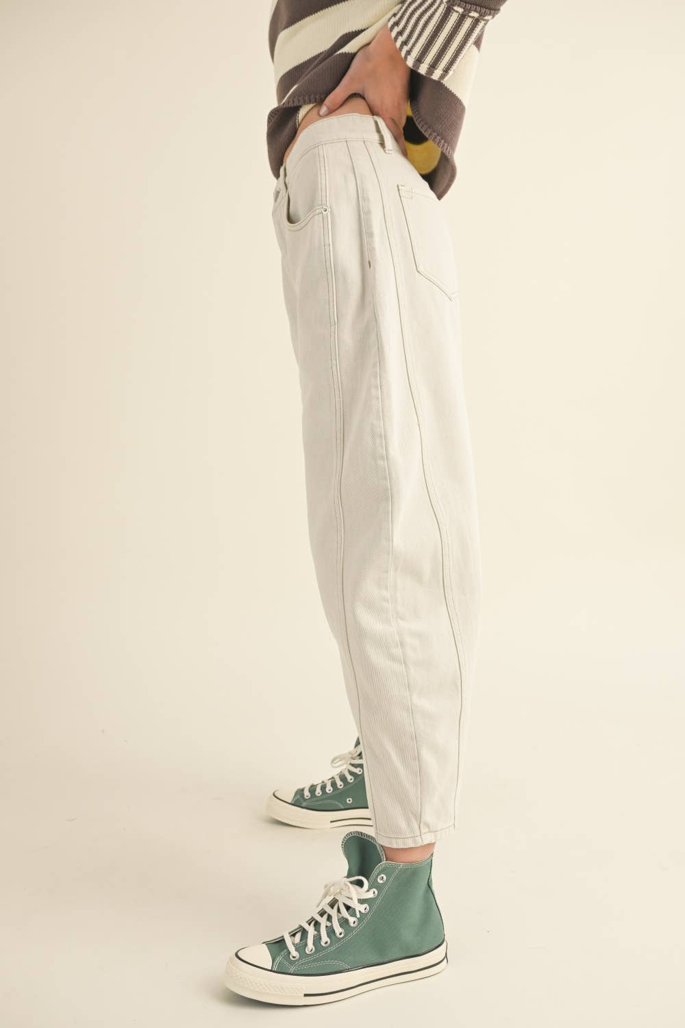 Person wearing white pants and green high-top sneakers on a beige background