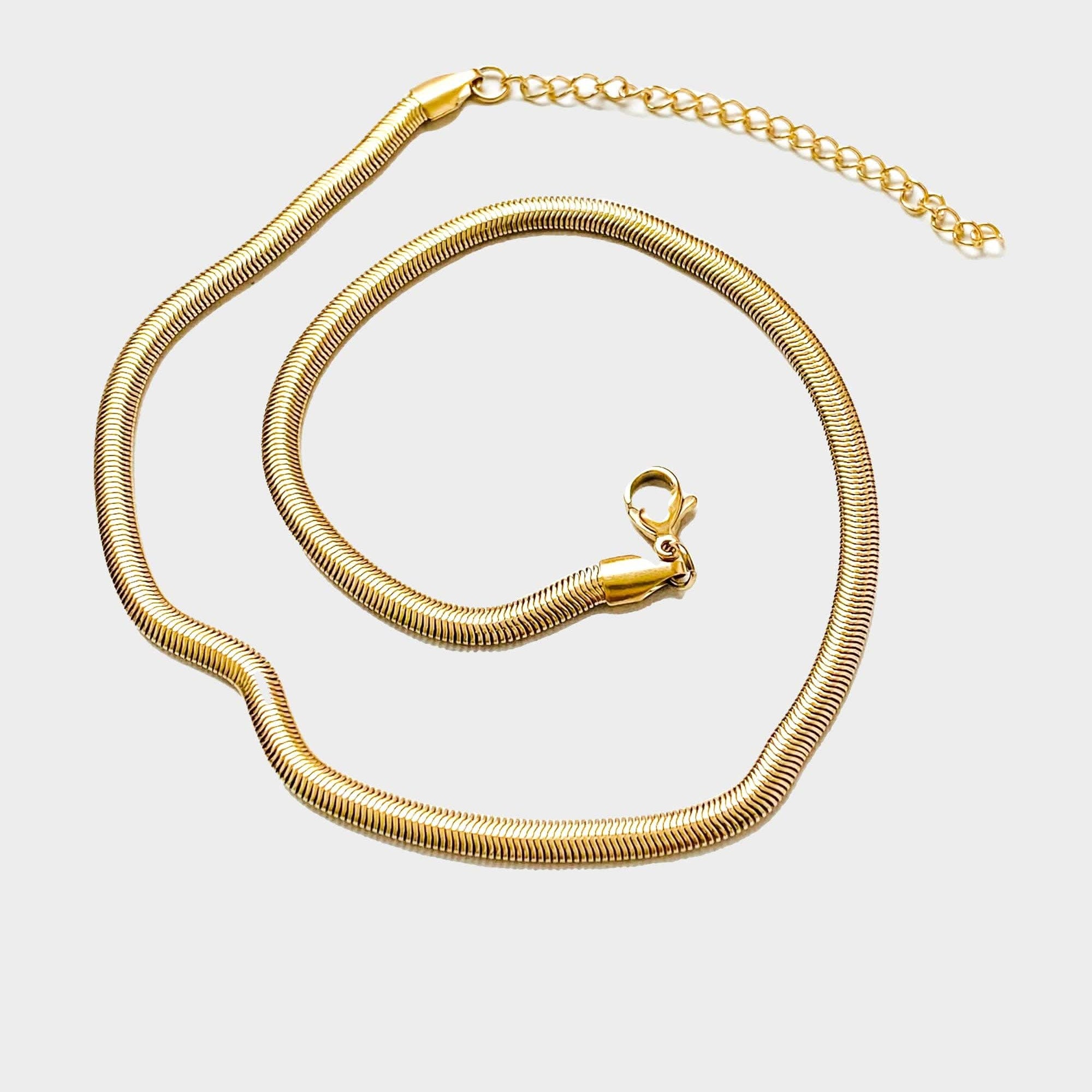 18k gold 15 inch to 17 inch herringbone necklace laid out in a swirl pattern on white background