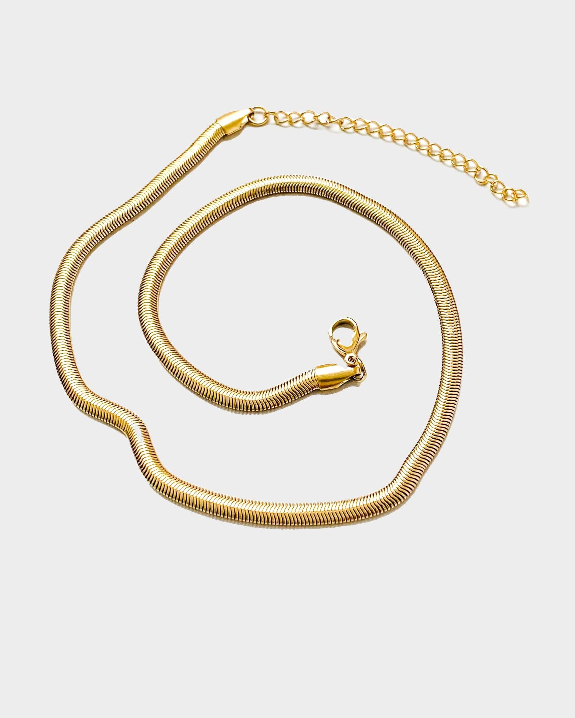 18k gold 15 inch to 17 inch herringbone necklace laid out in a swirl pattern on white background