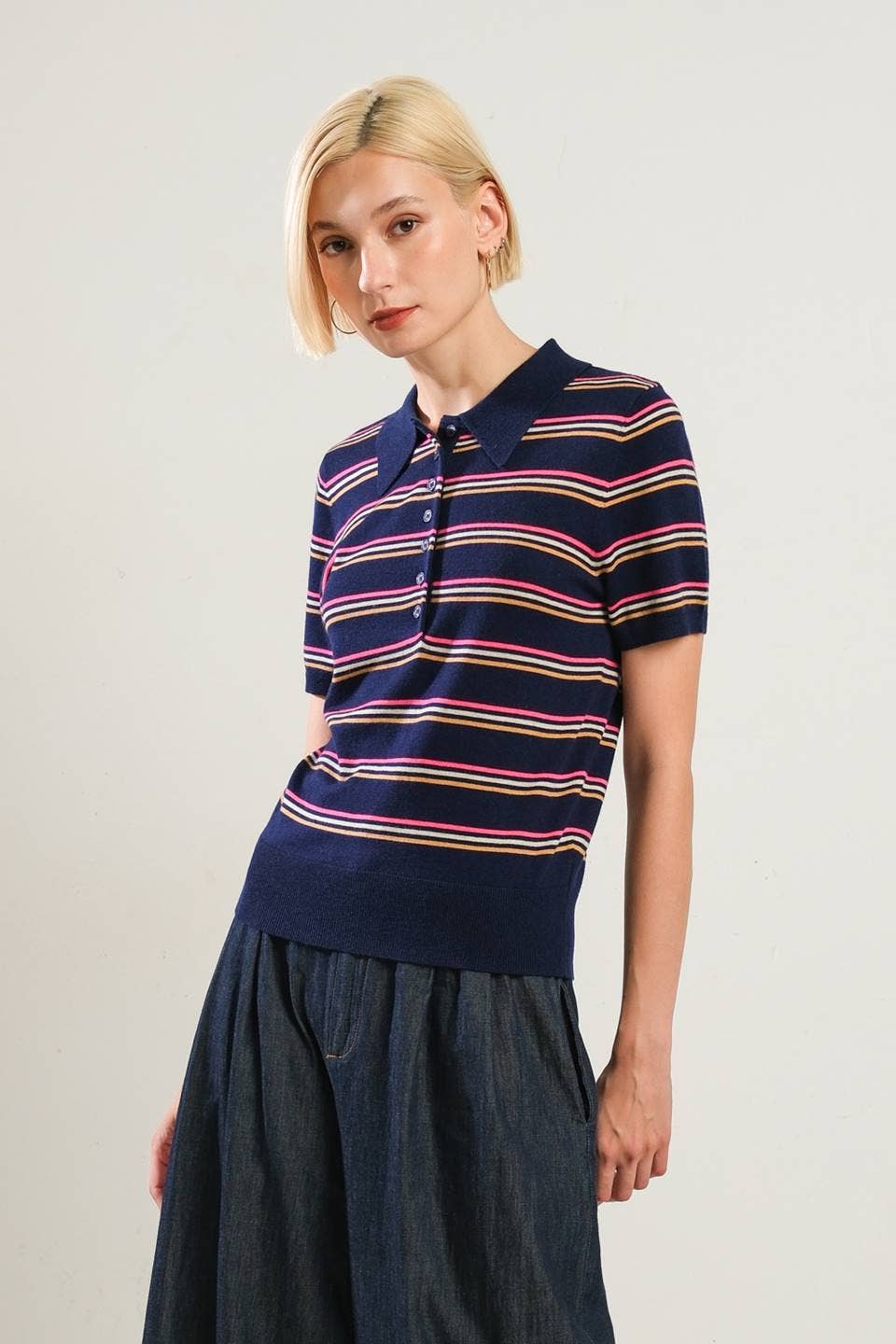 Woman wearing a navy striped polo shirt against a plain background