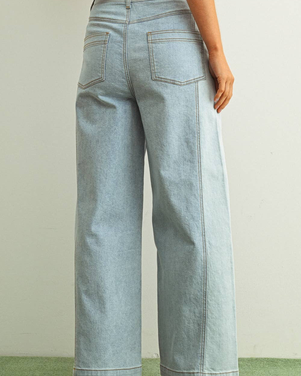 Woman wearing light denim jeans and light brown shoes standing behind a white background