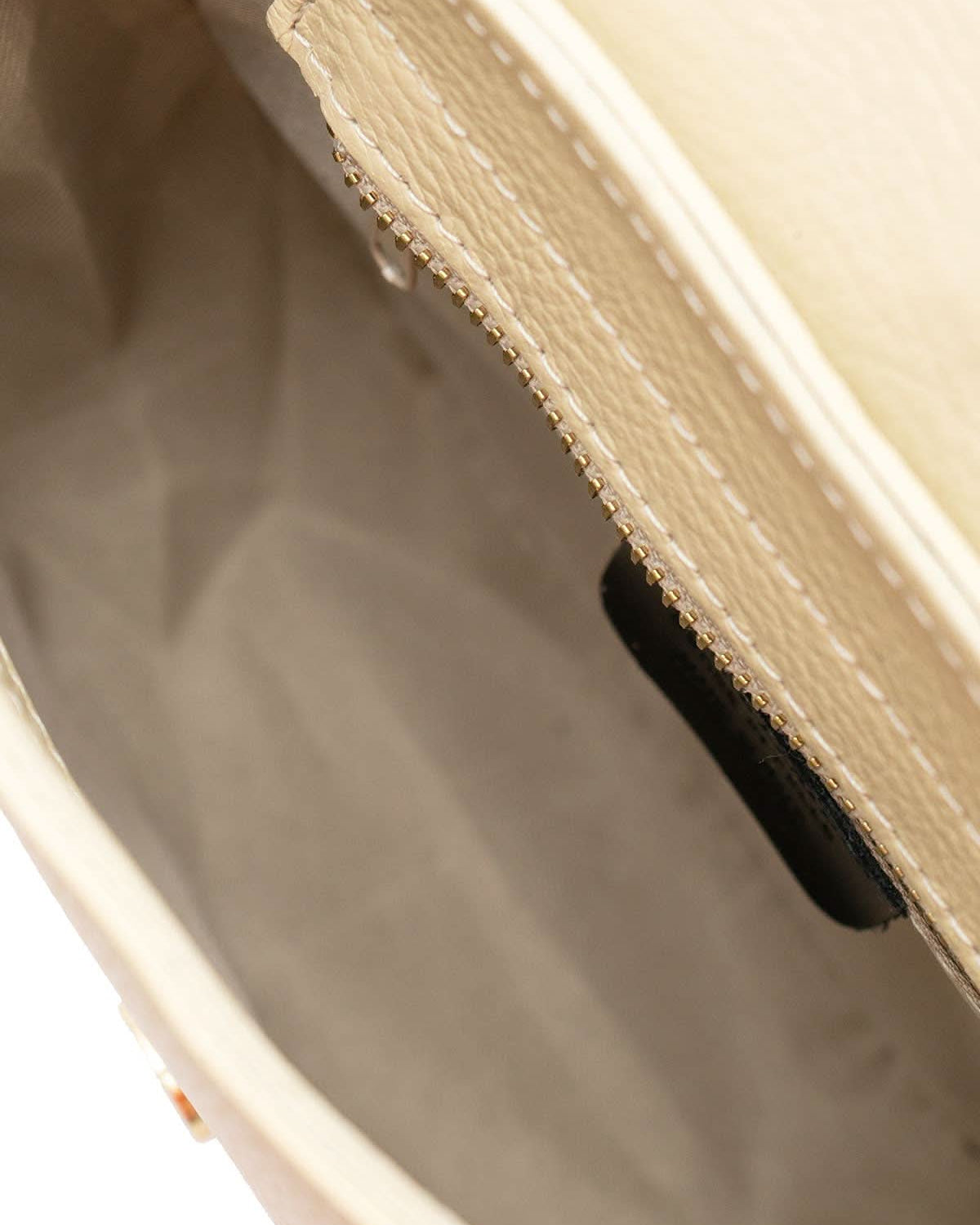 Inside view of Cream colored leather crossbody bag with magnetic front clap and leather woven geometric design and gold Metal details