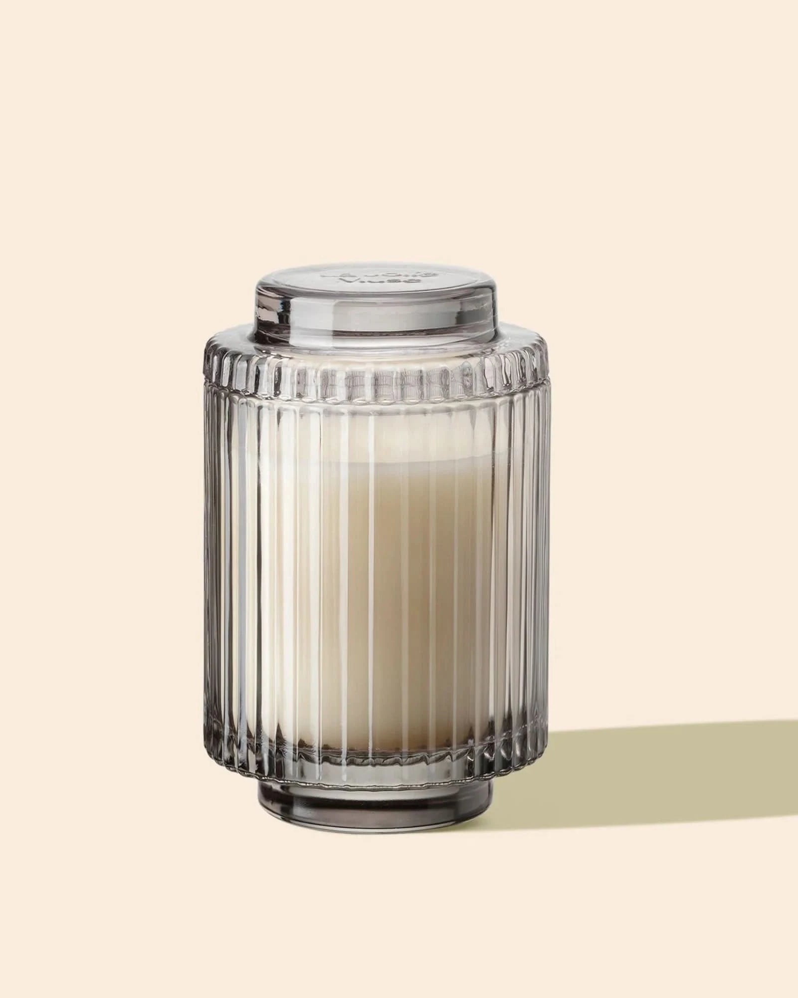 Decorative glass candle holder with a candle on a beige background