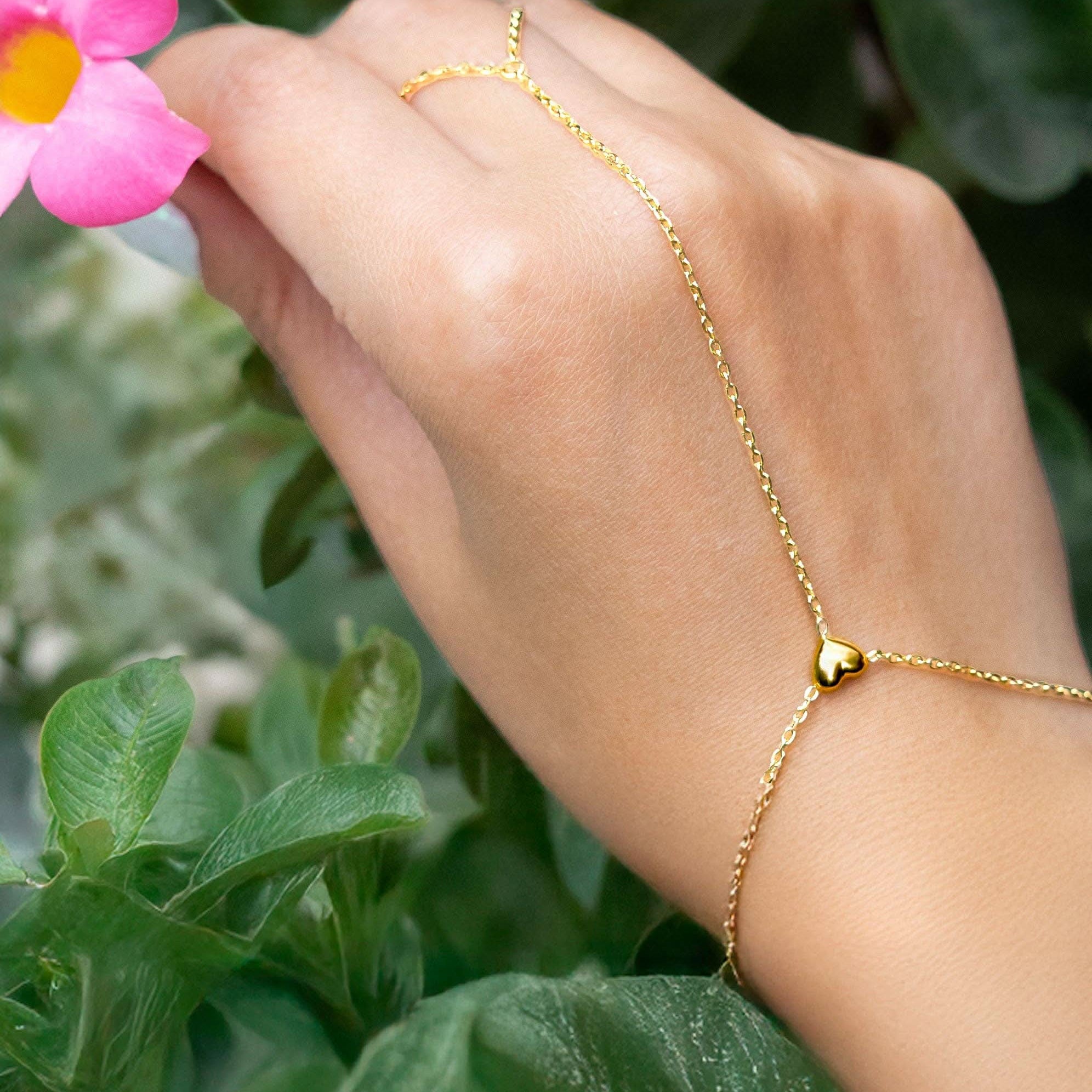 Delicate gold hand chain bracelet connected to a thin ring