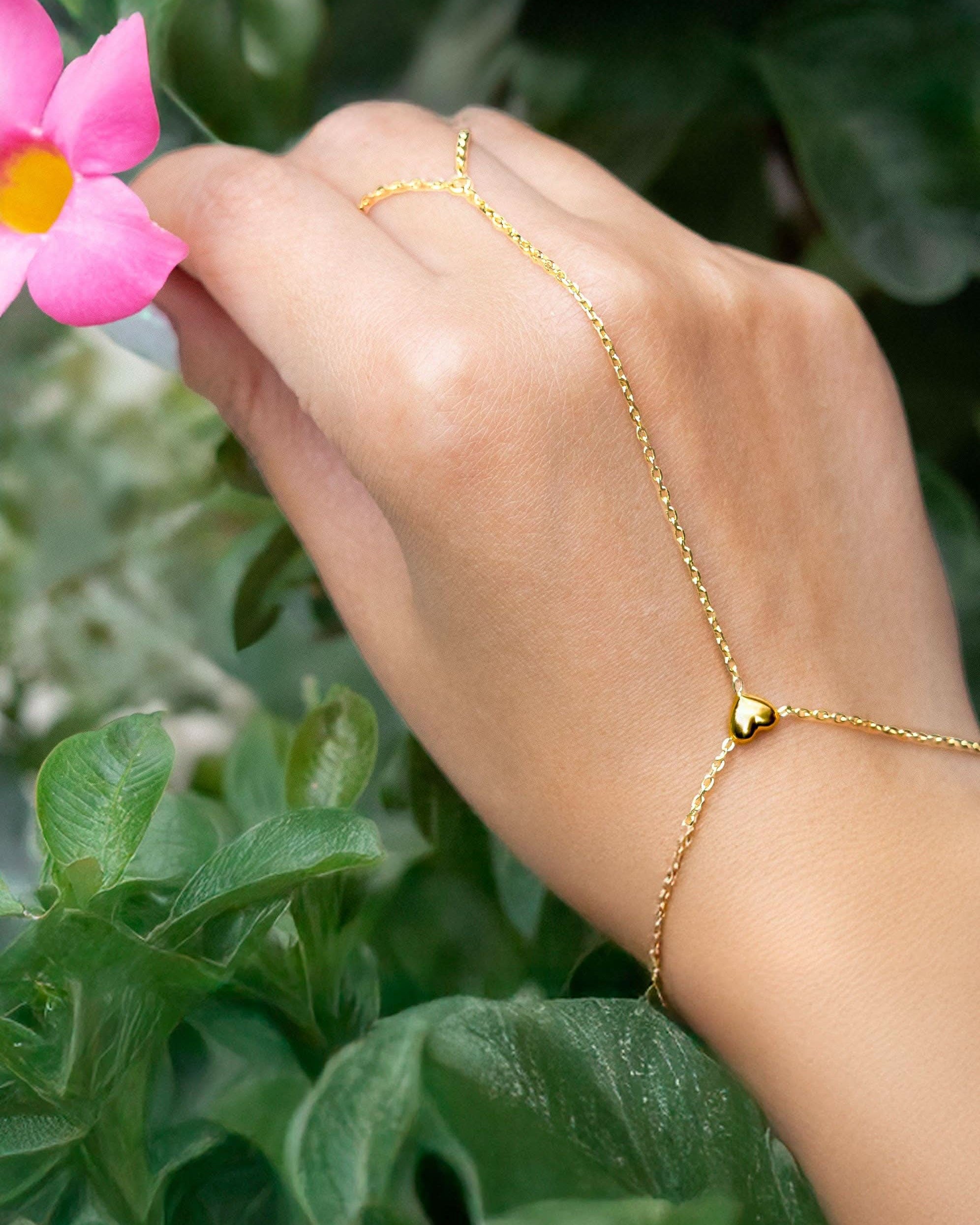 Delicate gold hand chain bracelet connected to a thin ring