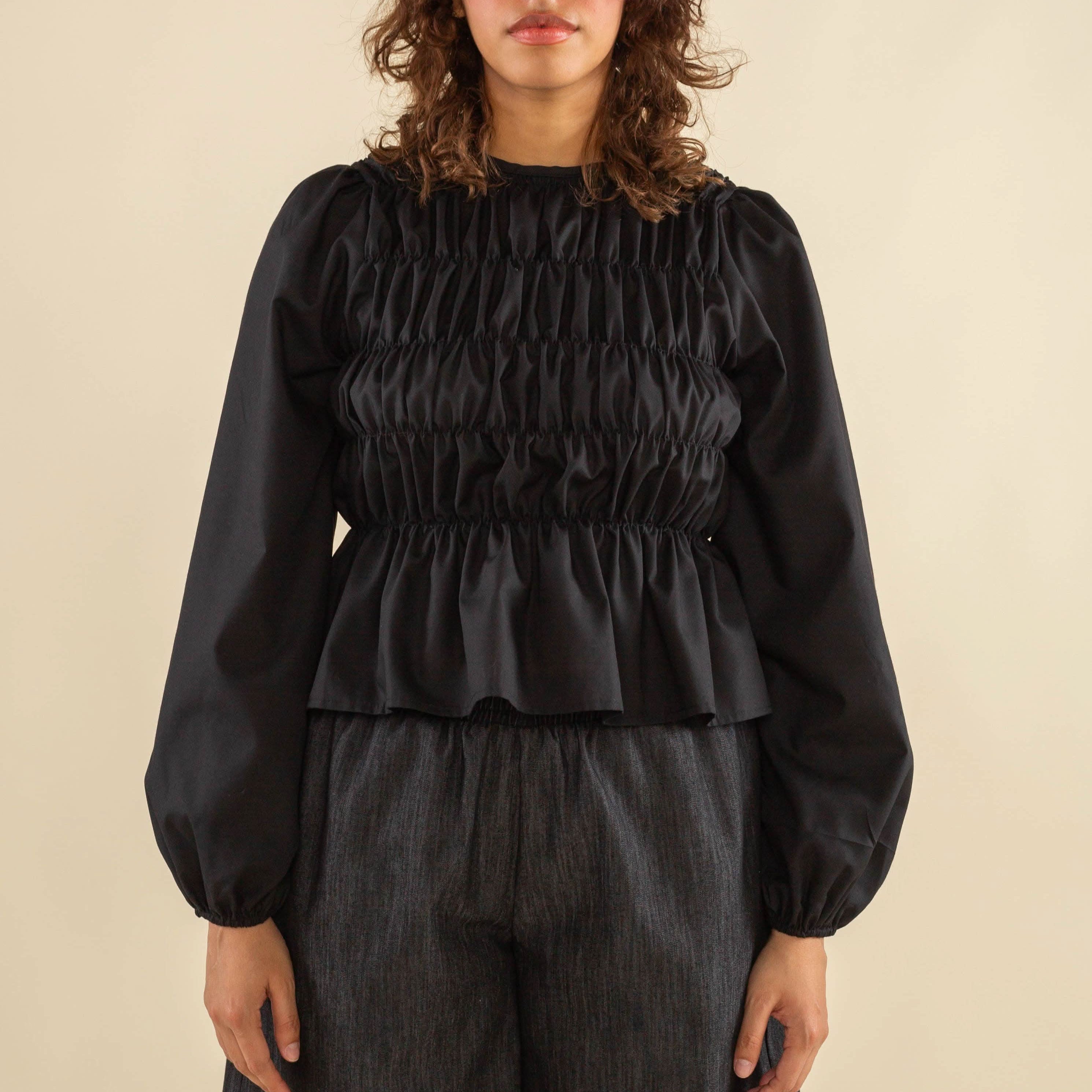 Woman wearing black, bubble long sleeve, shirred, peplum style top
