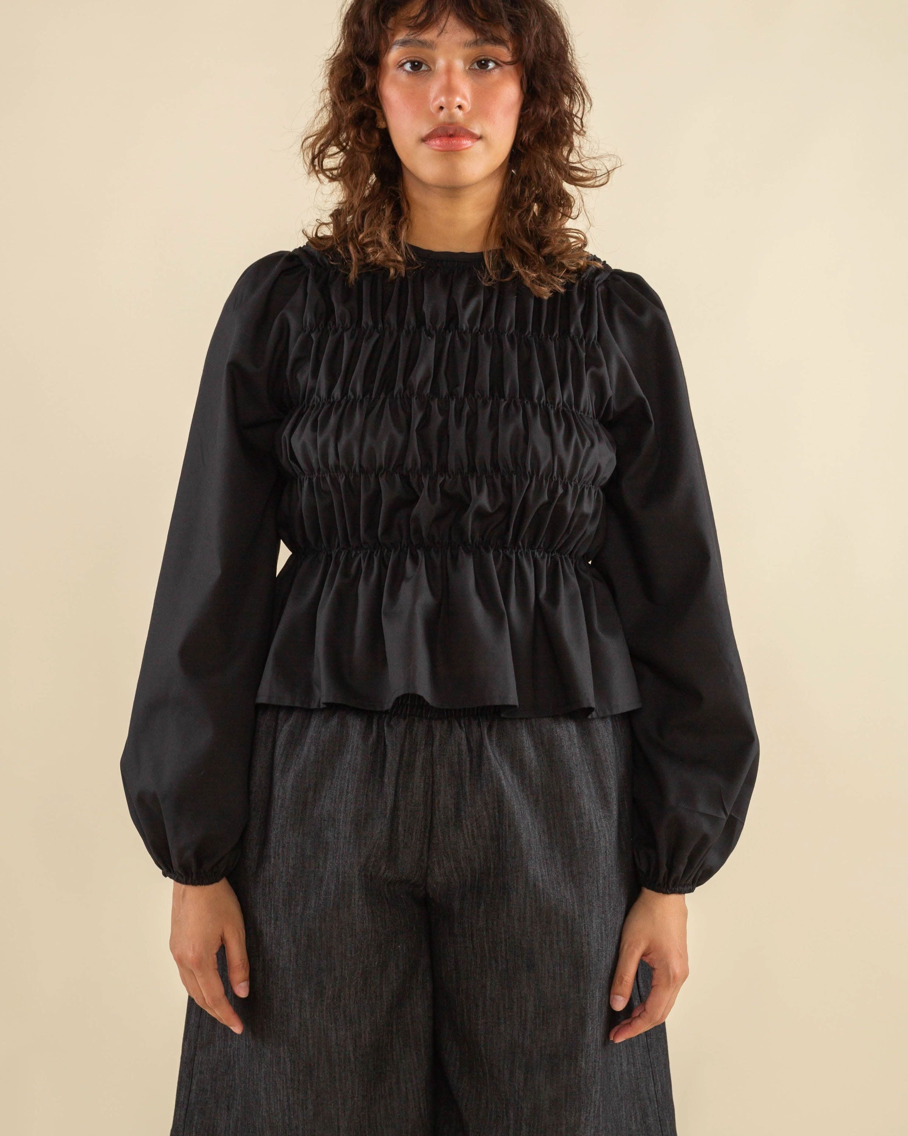 Woman wearing black, bubble long sleeve, shirred, peplum style top