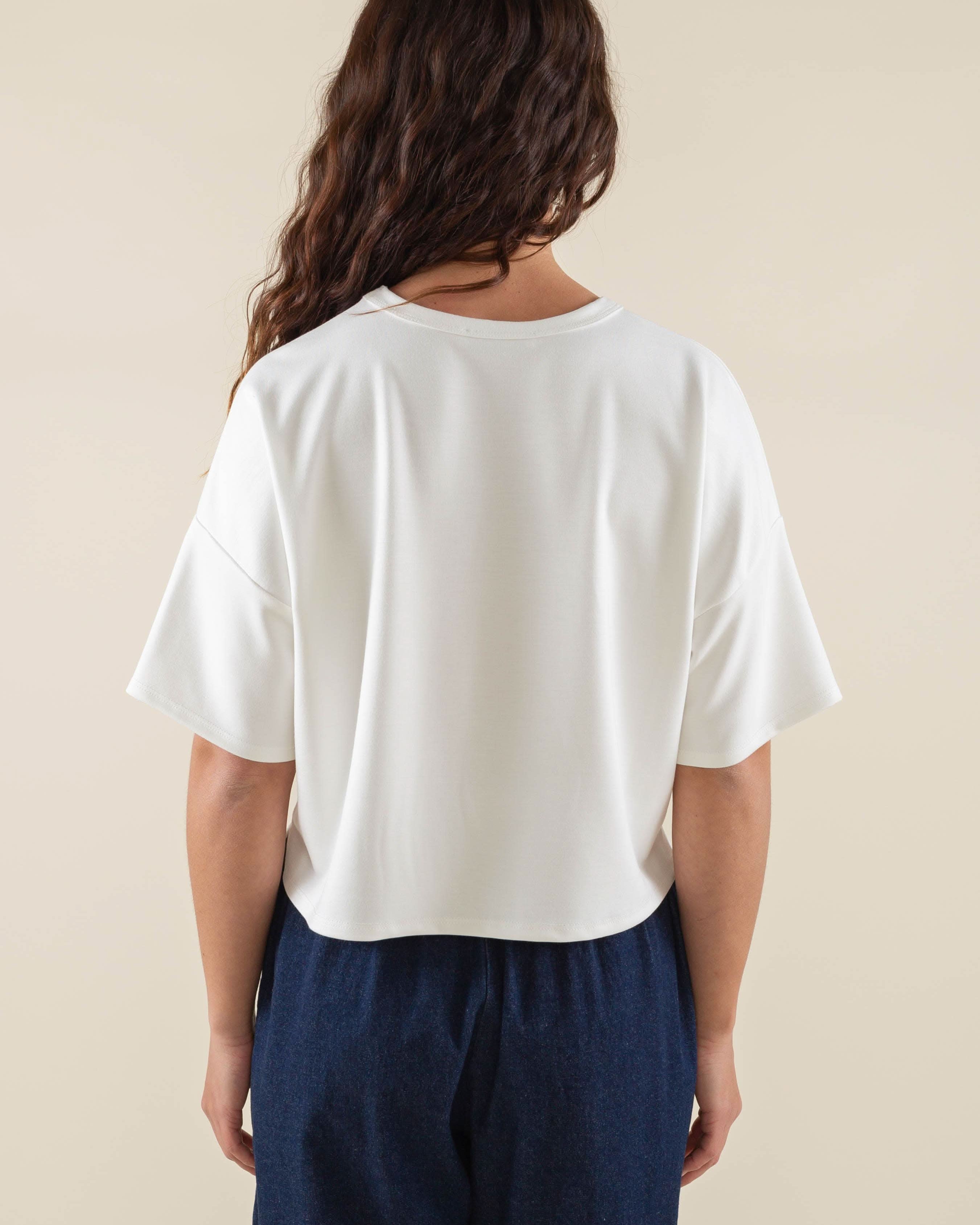 Woman wearing white, short sleeve, jersey, cropped t-shirt and blue jeans