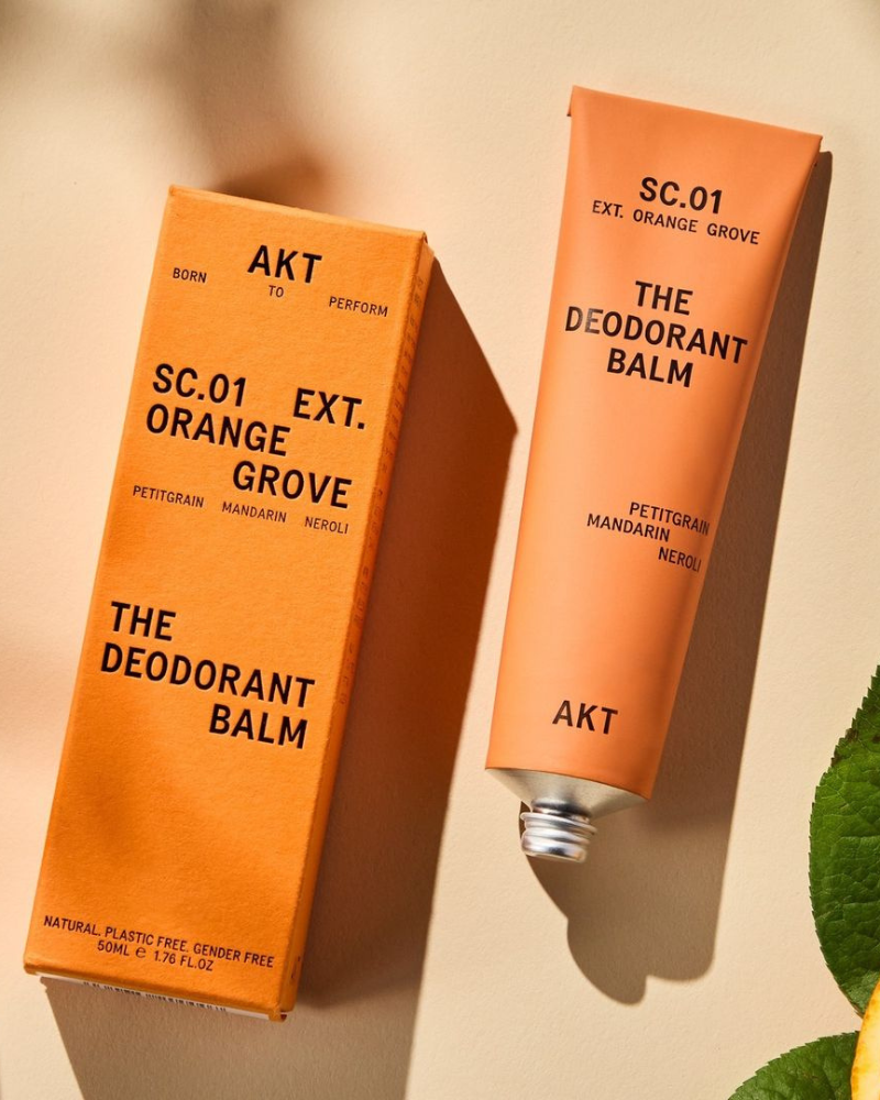 Orange grove deodorant balm in orange tube laying next to orange box packaging