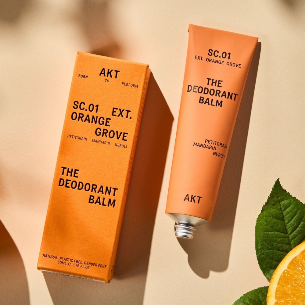 Orange grove deodorant balm in orange tube laying next to orange box packaging