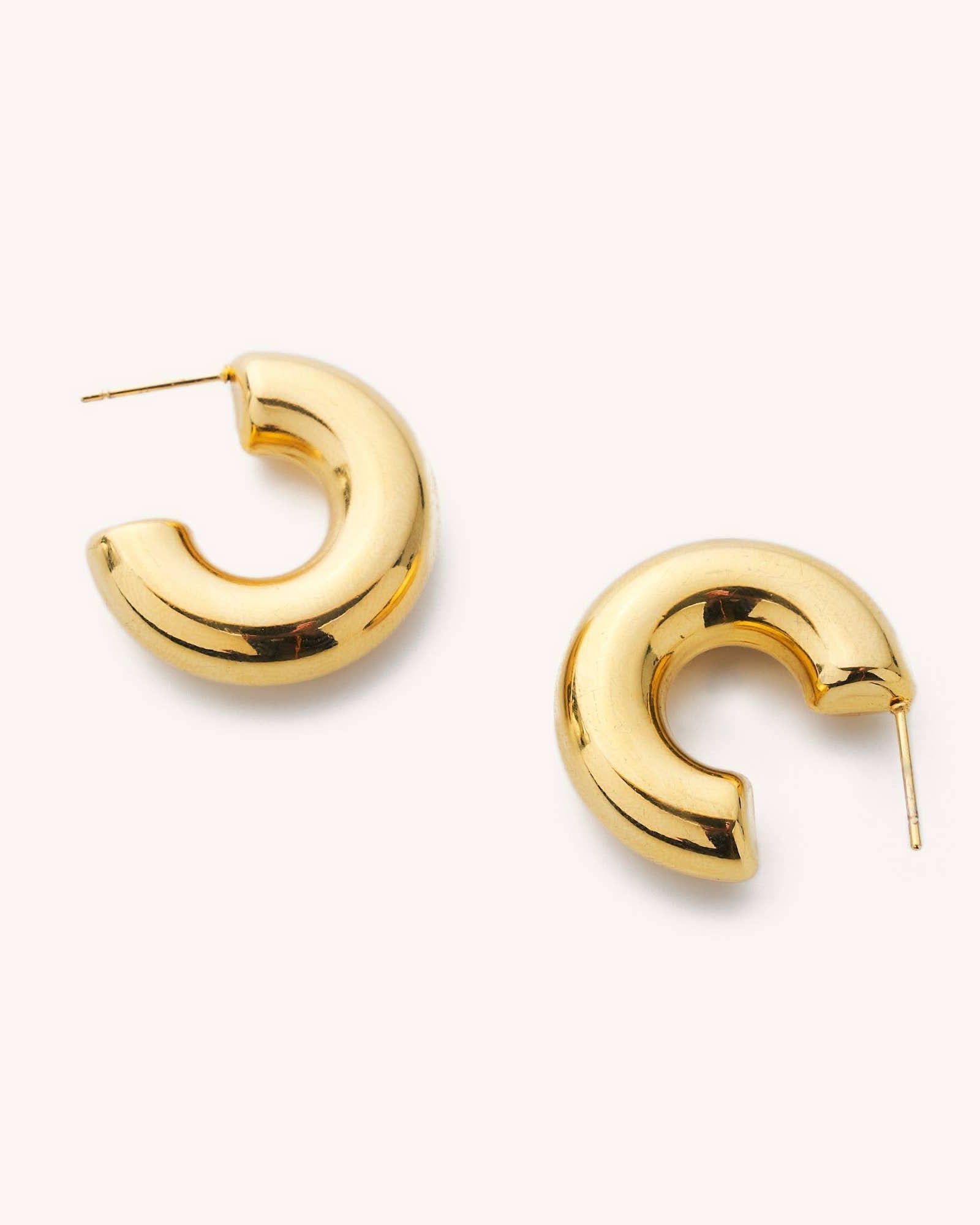 Chunky thick tube hoop earrings laying on a white background